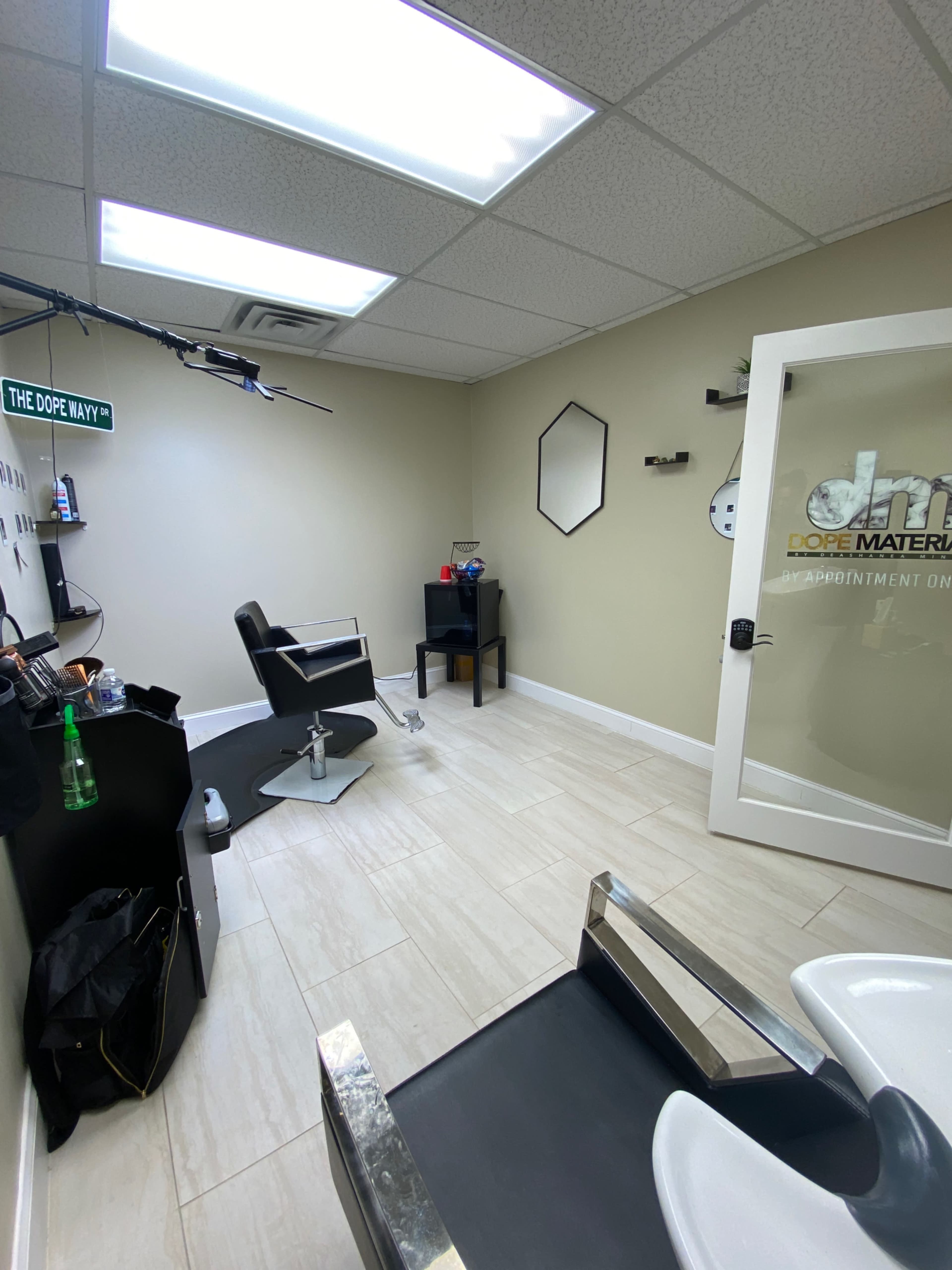 The image shows a modern hair salon interior featuring styling chairs, a shampoo station, and minimalist decor.