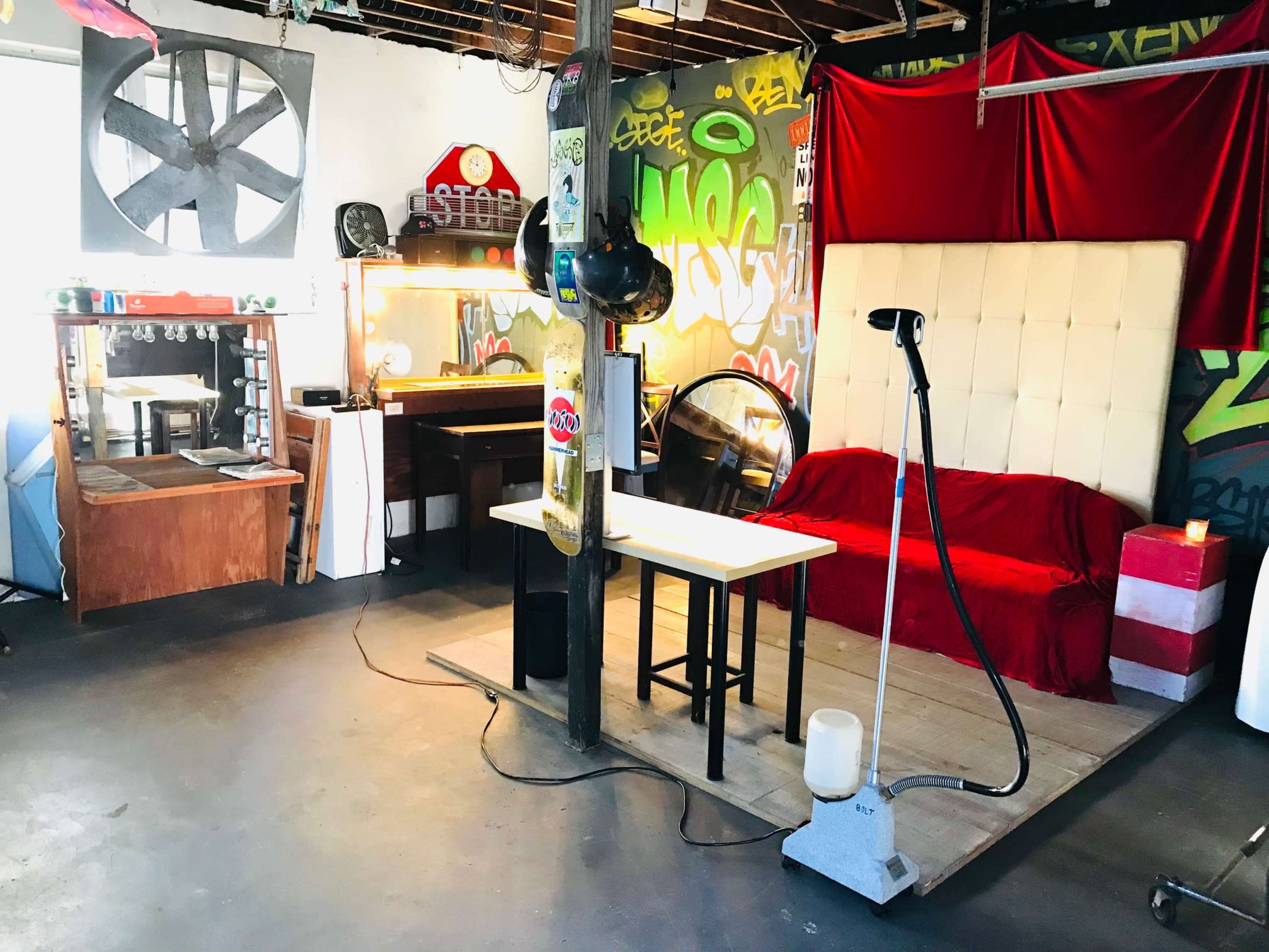 The image shows a creative workspace with a red couch, a table, and various artistic decorations on the walls.