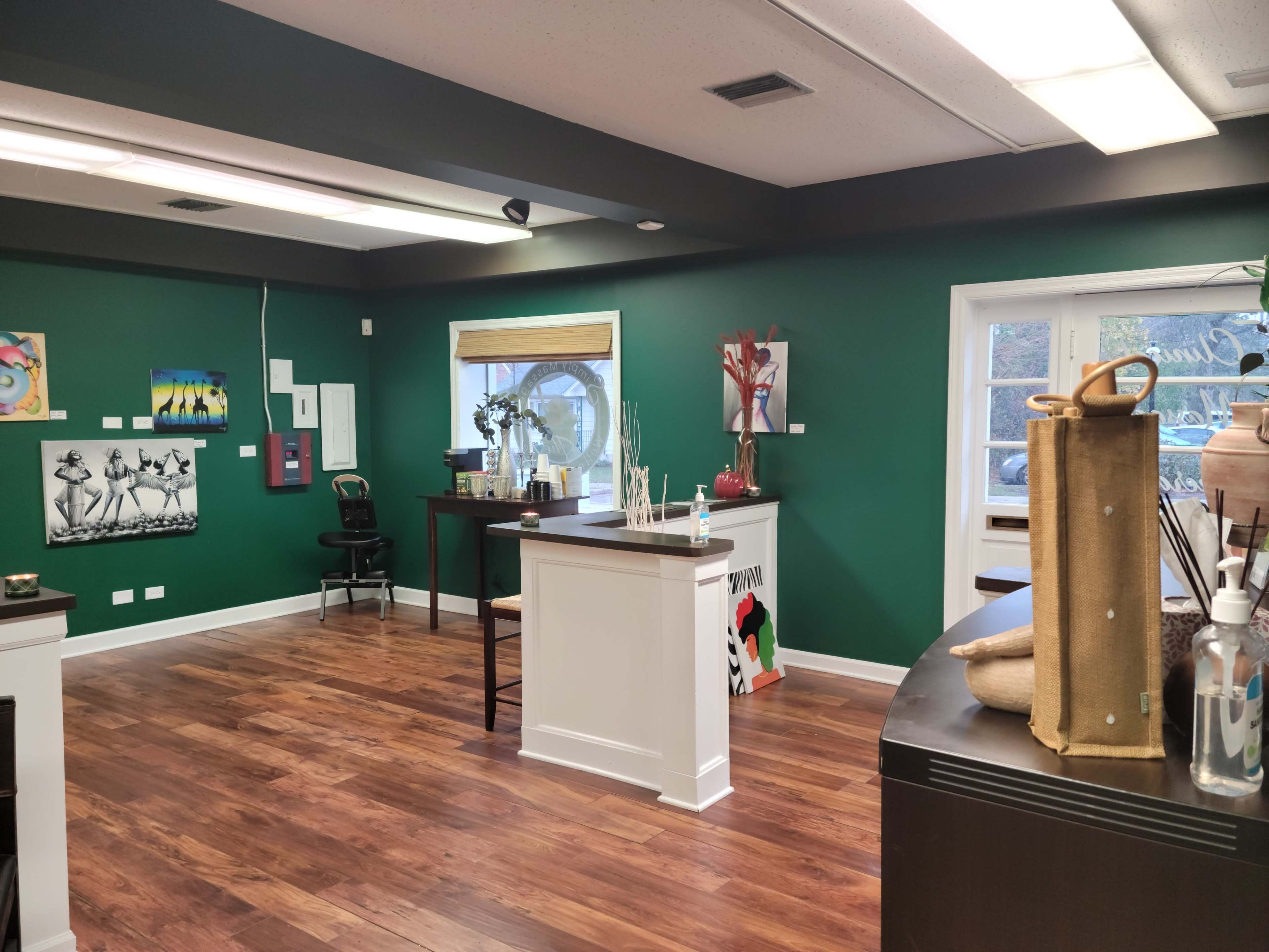 An art gallery featuring green walls, wooden flooring, and various artworks displayed throughout the space.