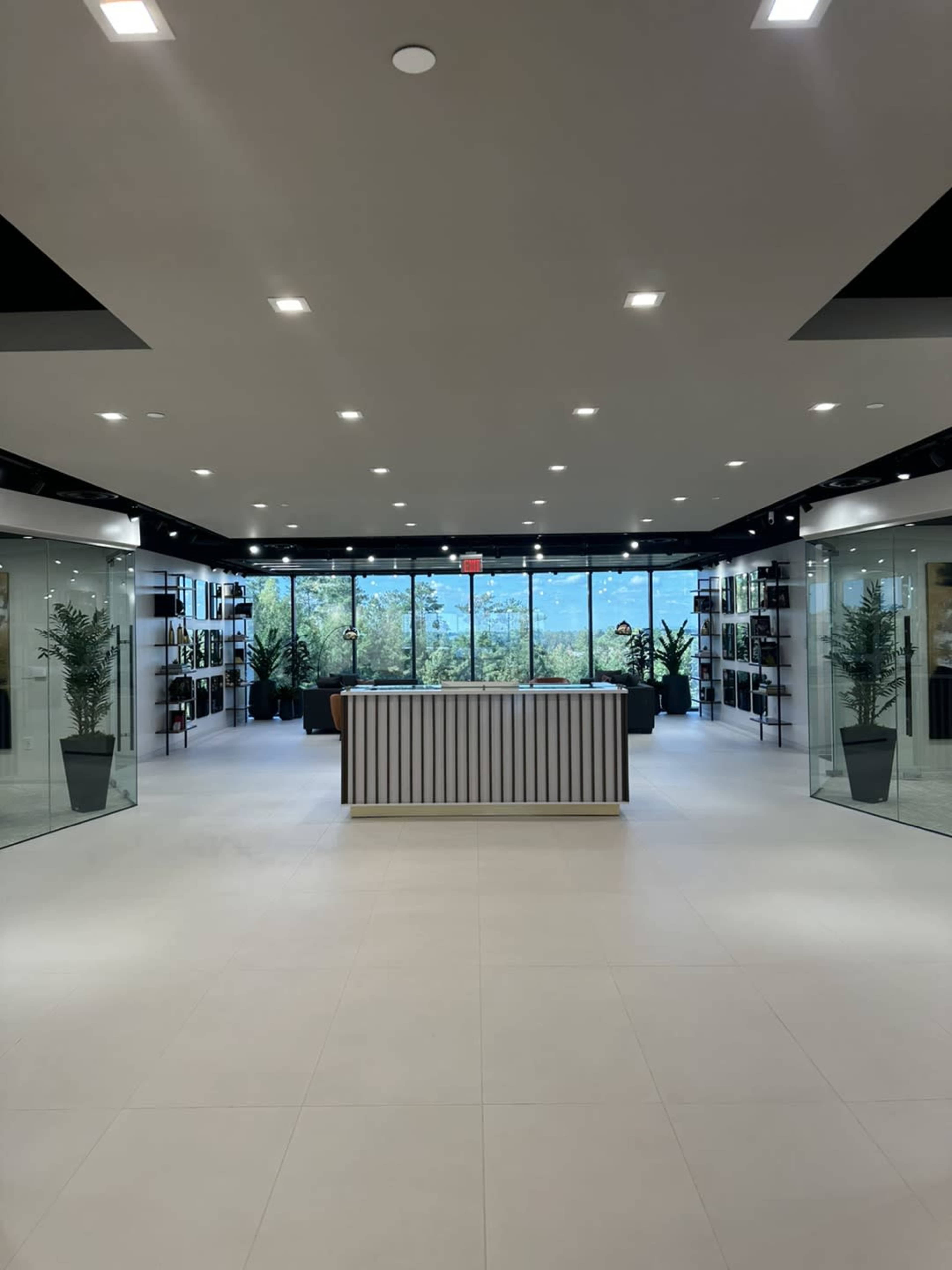 A modern, well-lit interior space with a central reception desk and large windows offering views of greenery outside.