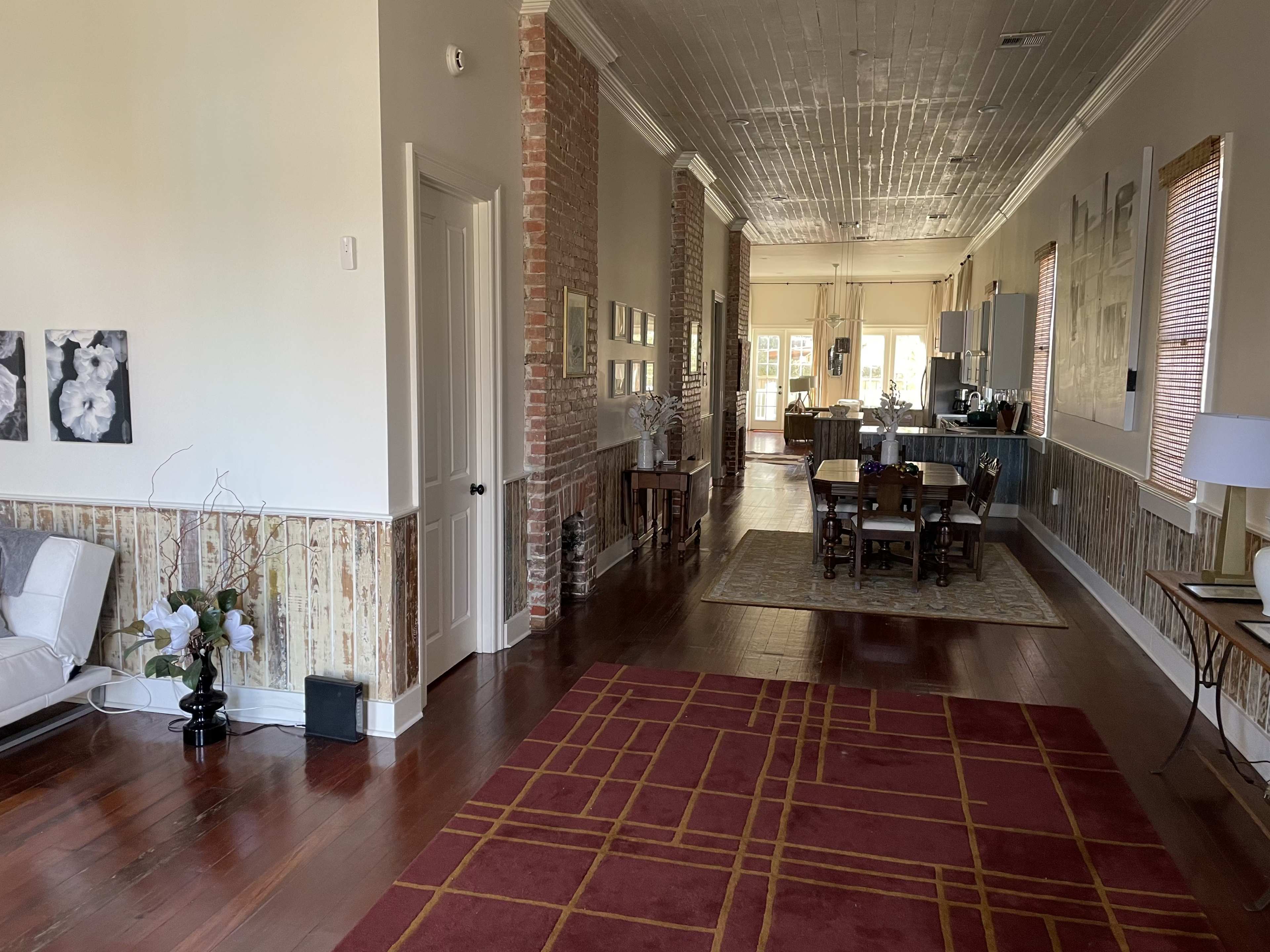 A spacious interior with hardwood floors, exposed brick walls, and a dining area visible in the background.