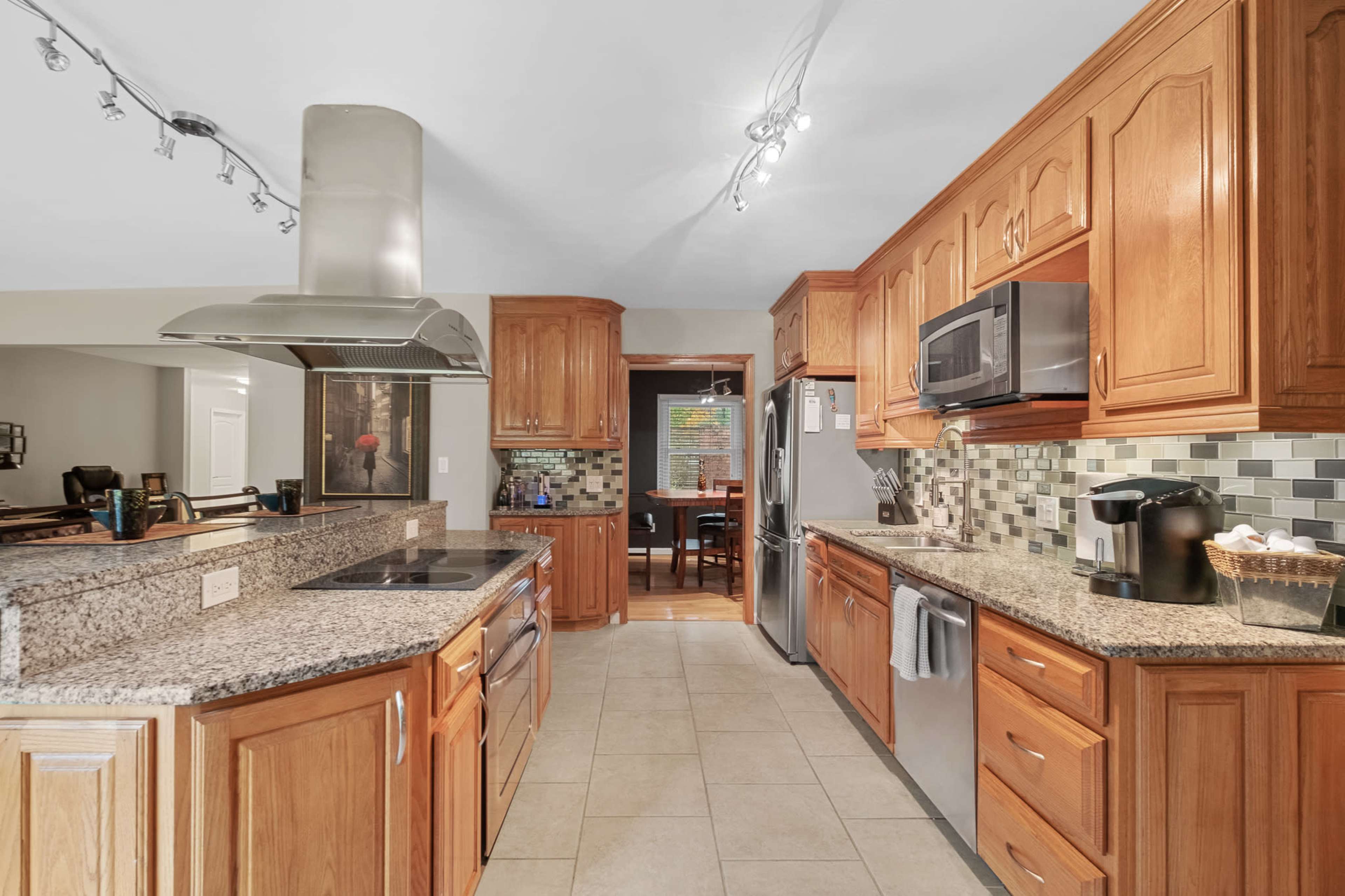 The kitchen features wooden cabinetry, granite countertops, and stainless steel appliances with a tiled backsplash.