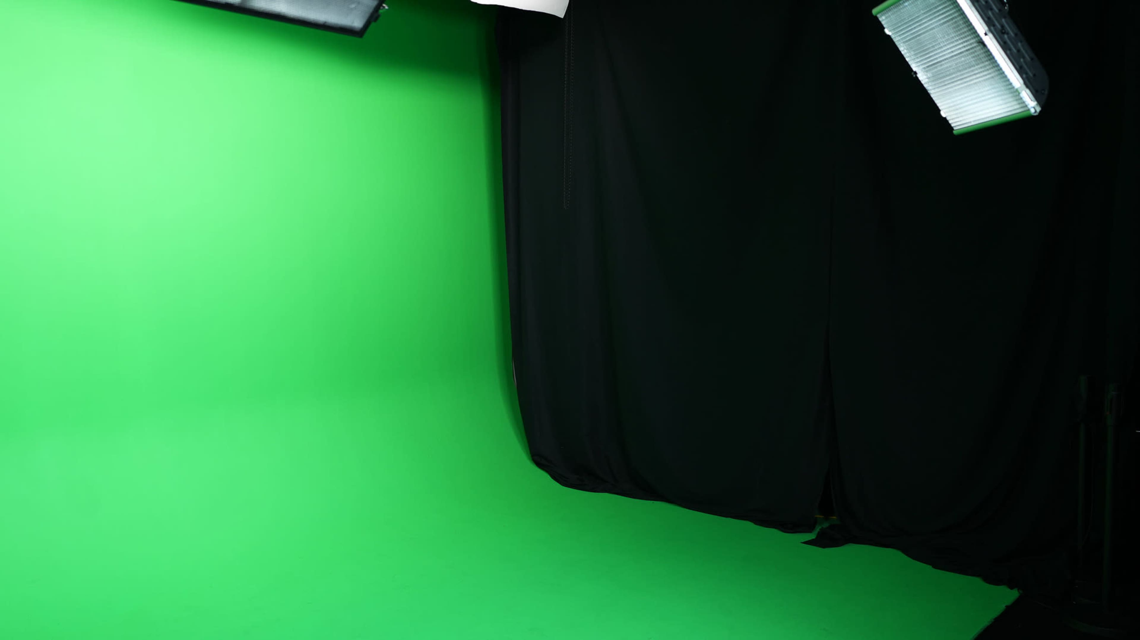 A green screen setup next to a black curtain in a studio environment.