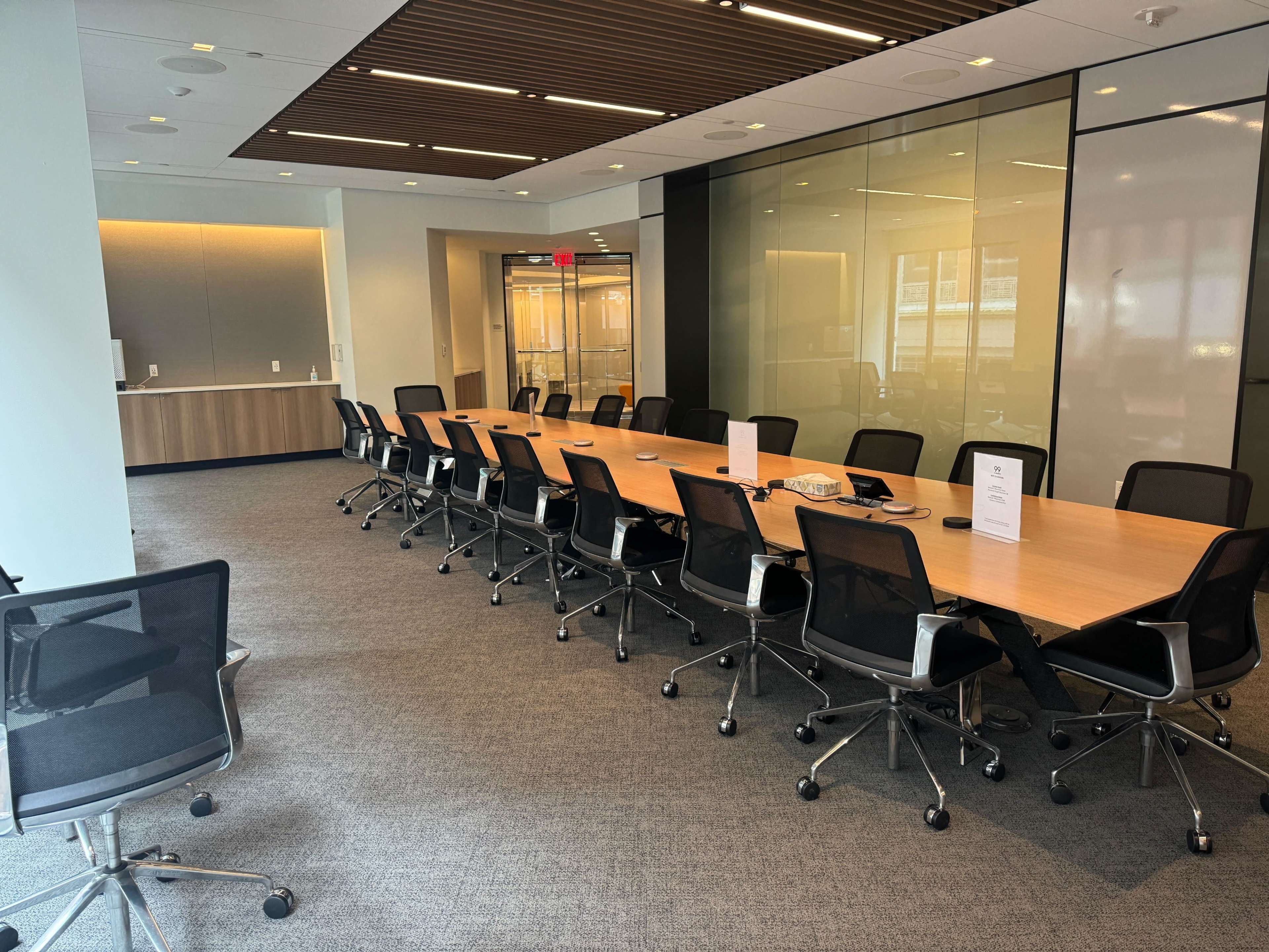 A long conference table with rolling chairs is set up in a well-lit modern meeting room.