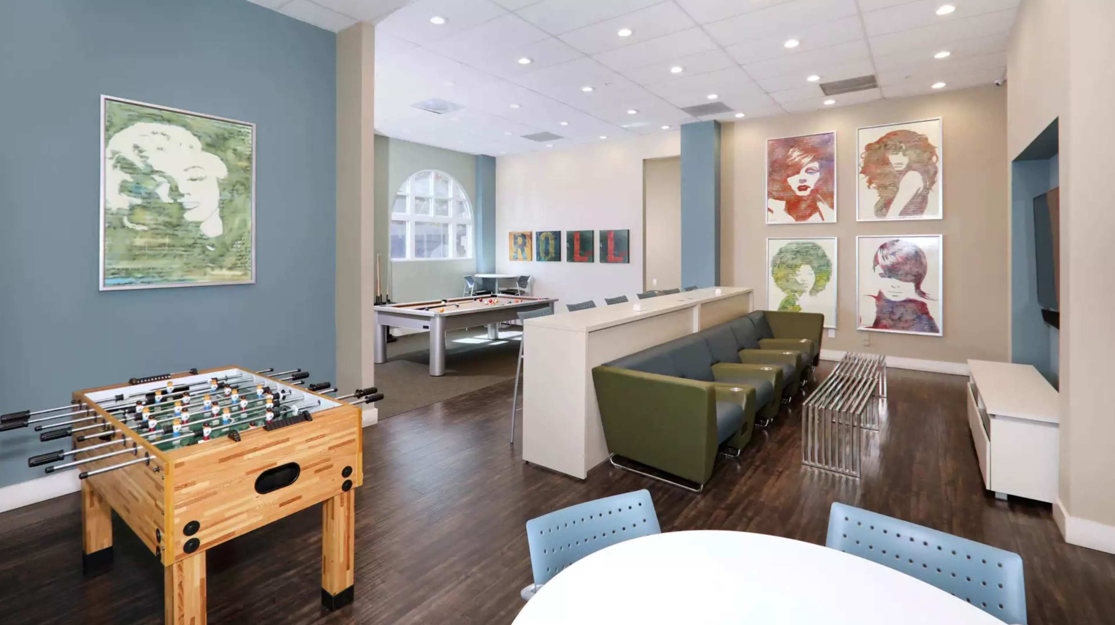 A spacious recreational lounge area featuring a foosball table, a seating arrangement, and artwork on the walls.