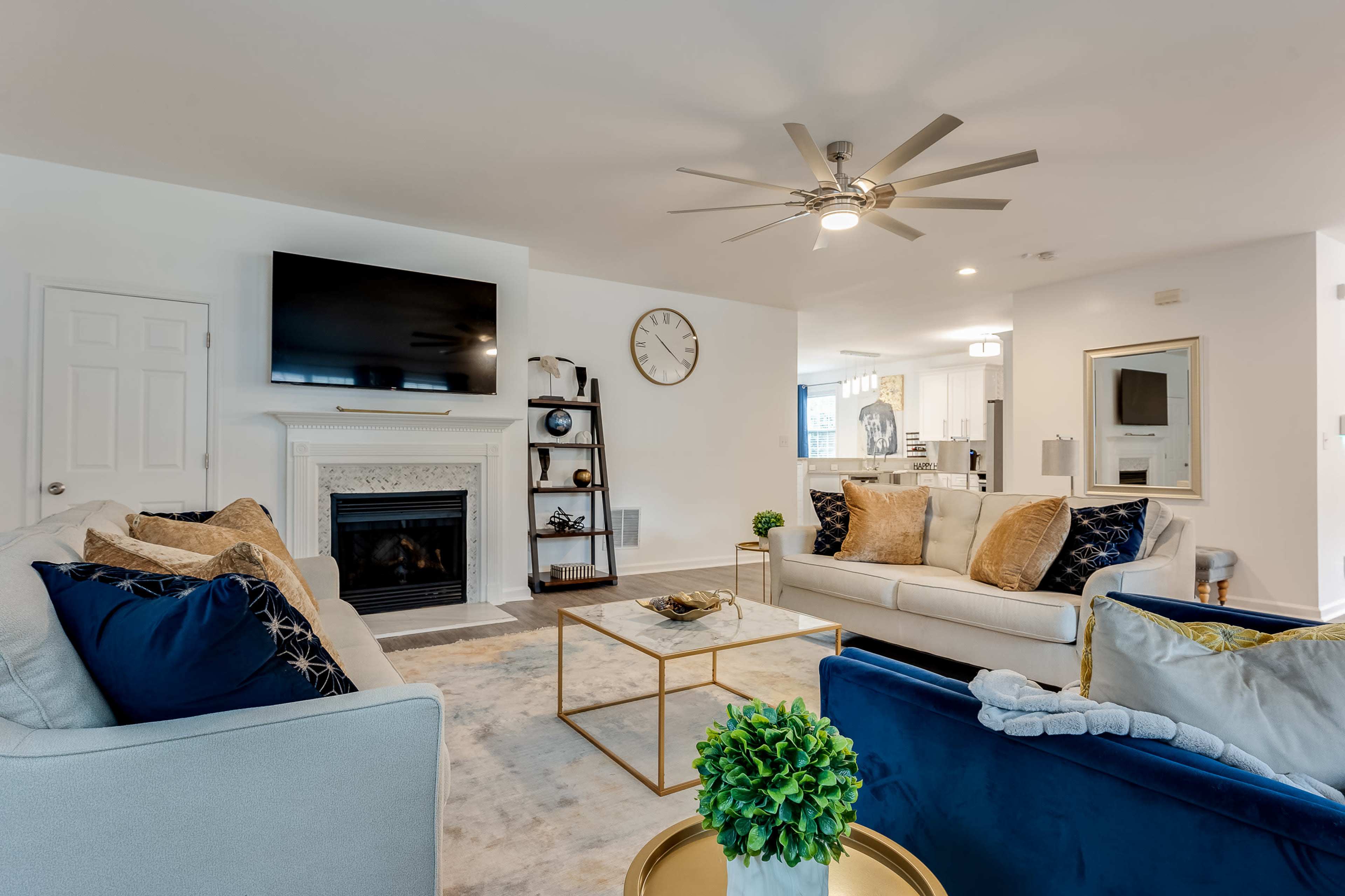 The living room features a fireplace with a television above it, surrounded by two sofas, a coffee table, and decorative elements.