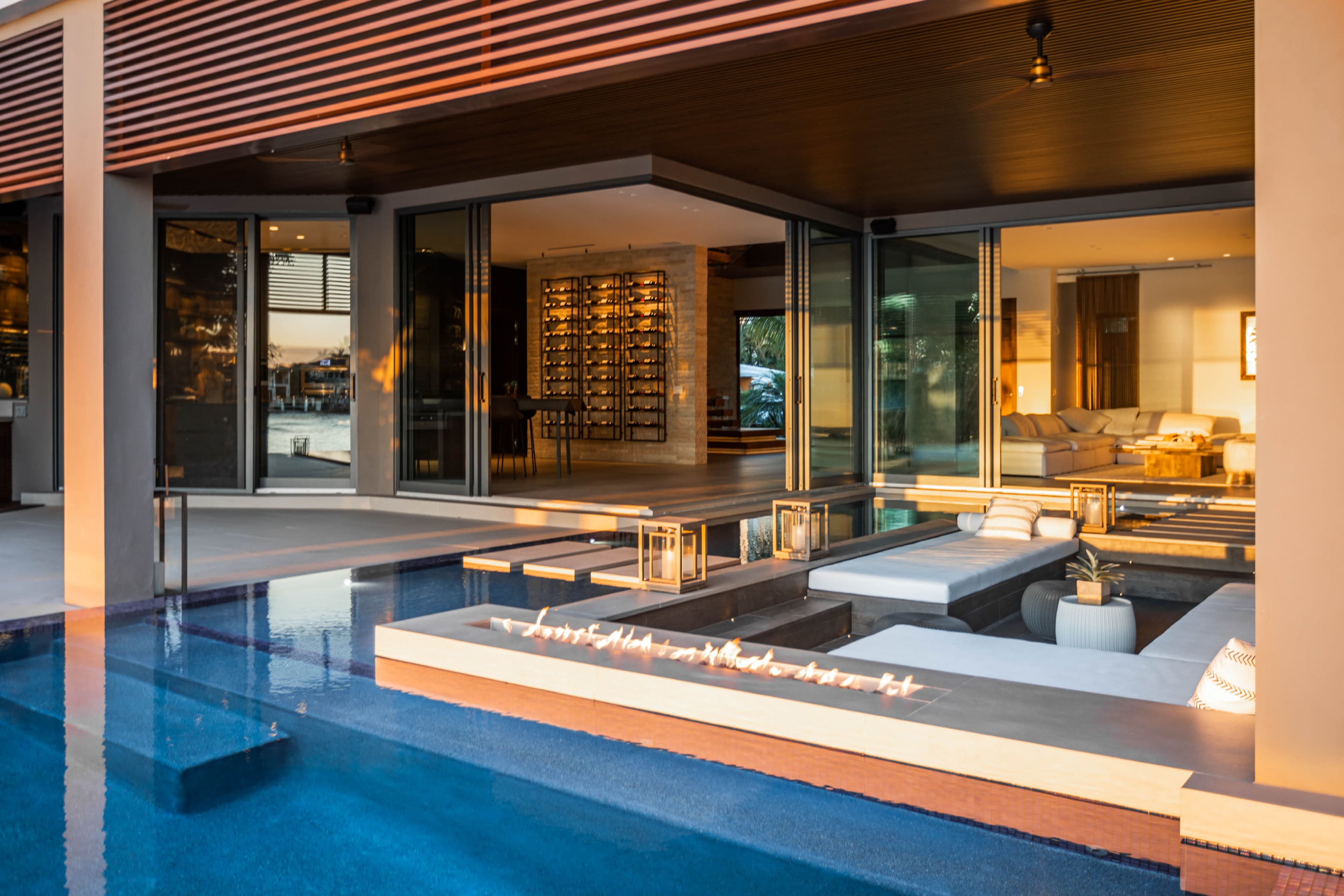 A modern waterfront home with a swimming pool, featuring an open living space that connects to an outdoor patio.