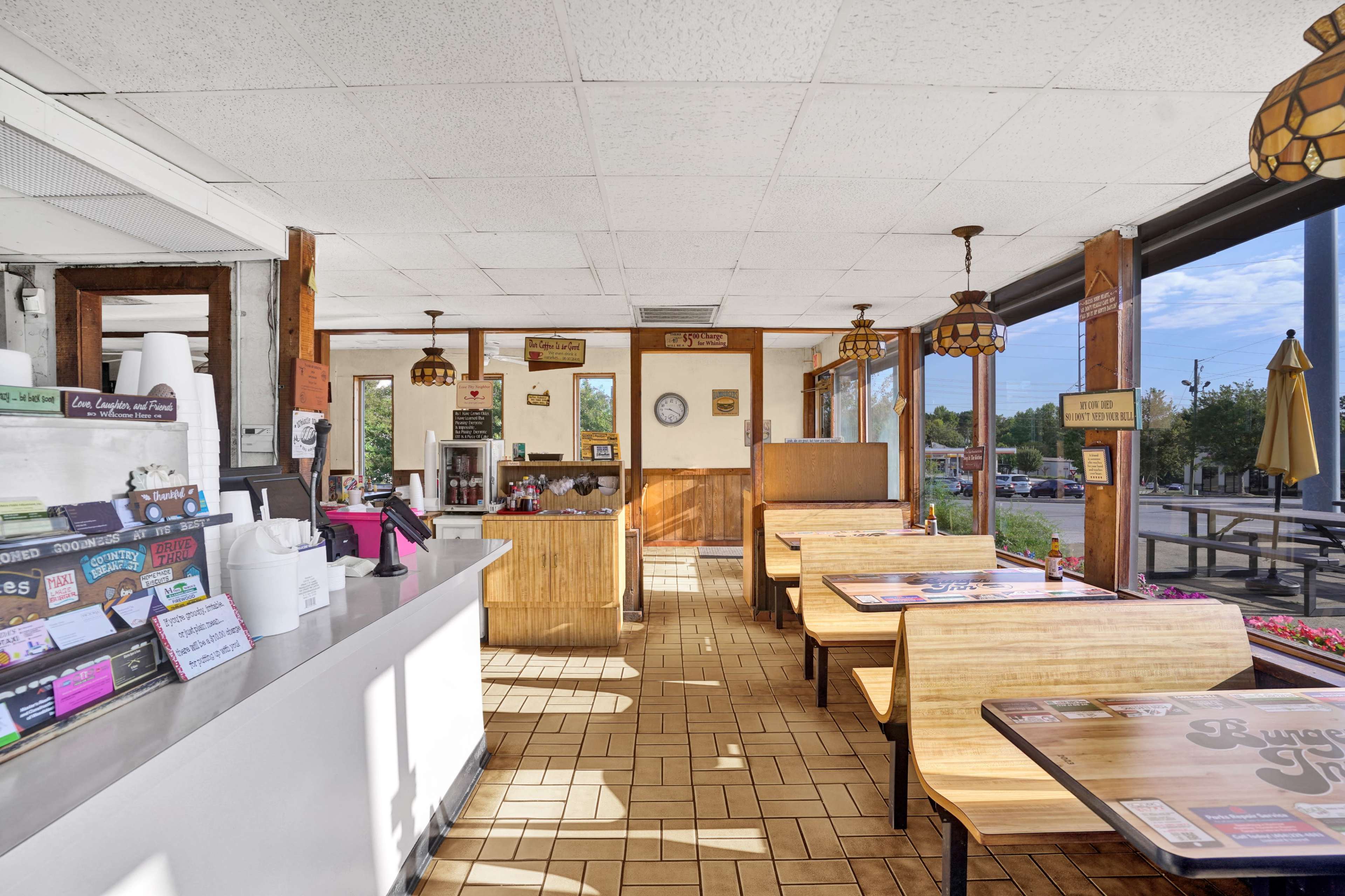 The image shows the interior of a casual dining restaurant, featuring wooden tables, vintage decor, and a service counter with various menu items displayed.