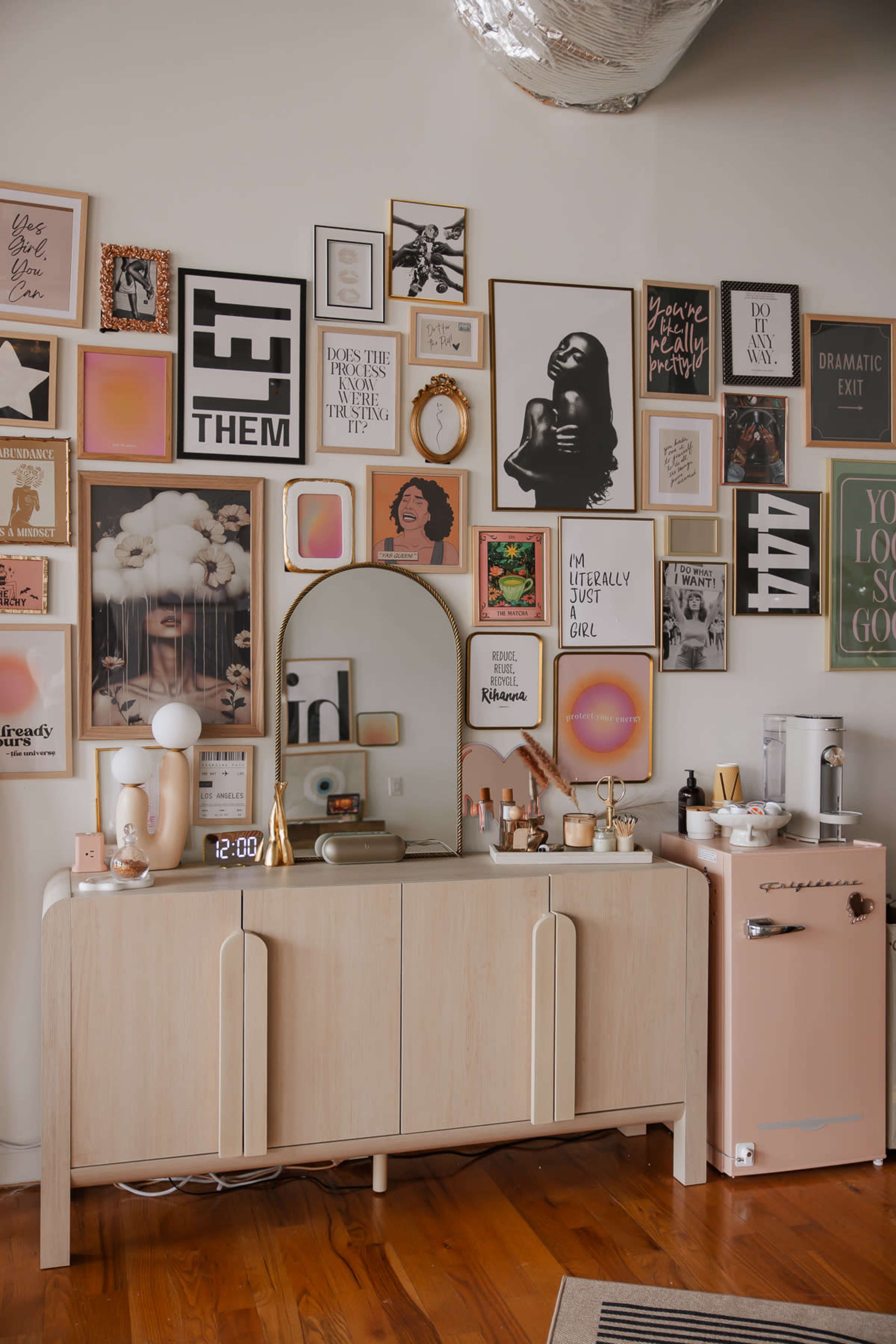 The image features a stylish mid-century modern sideboard adorned with decorative items, a round mirror, and a collection of framed artwork arranged on the wall above it.