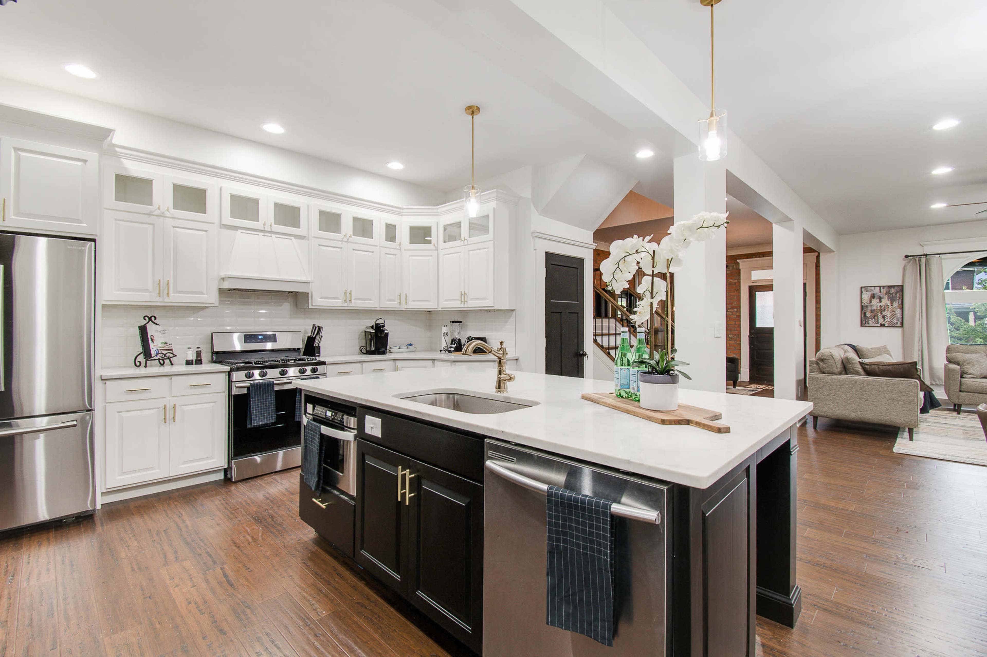 A modern kitchen featuring white cabinetry, stainless steel appliances, and an island with a dark countertop.