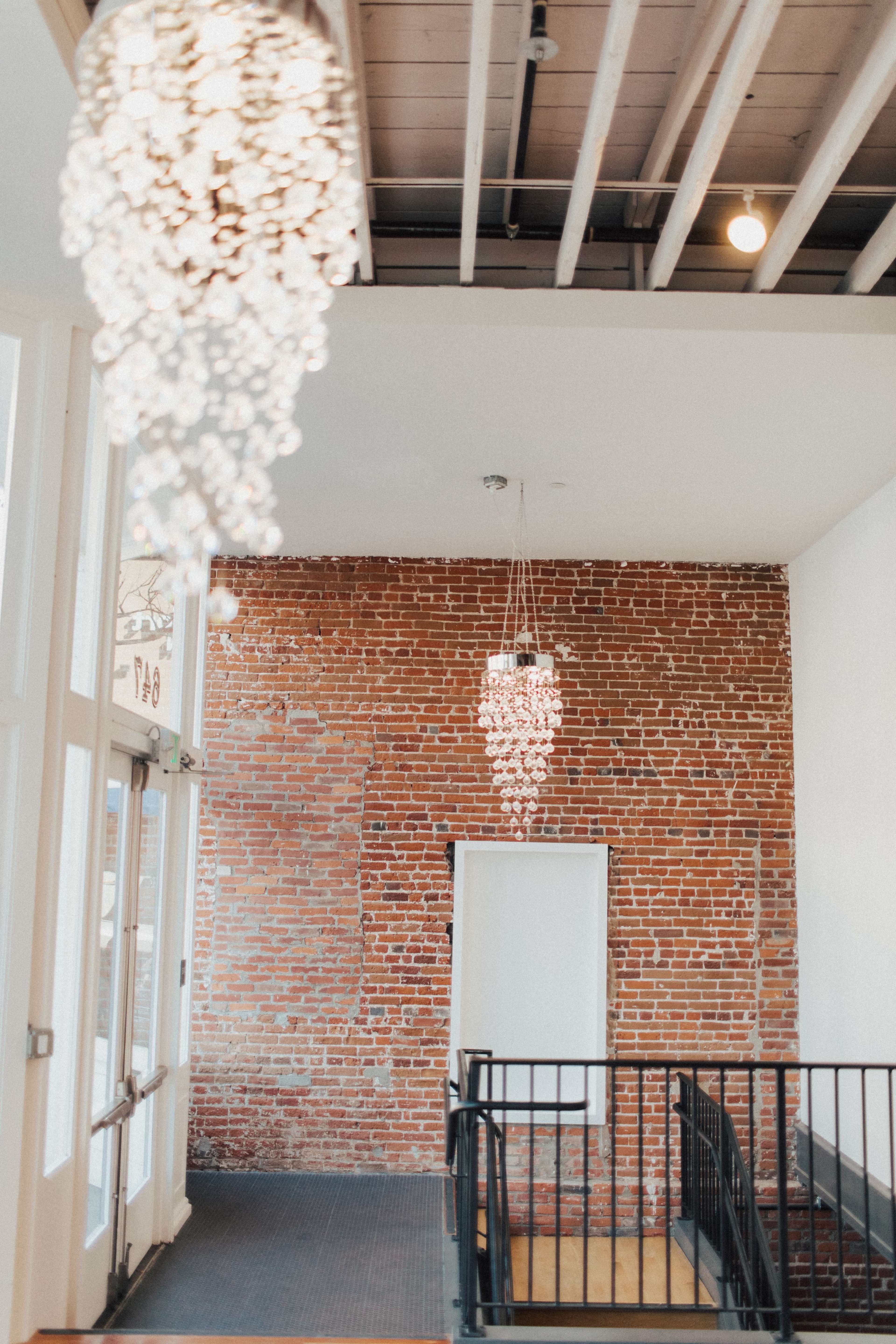 A modern interior features exposed brick walls and two sleek hanging light fixtures.