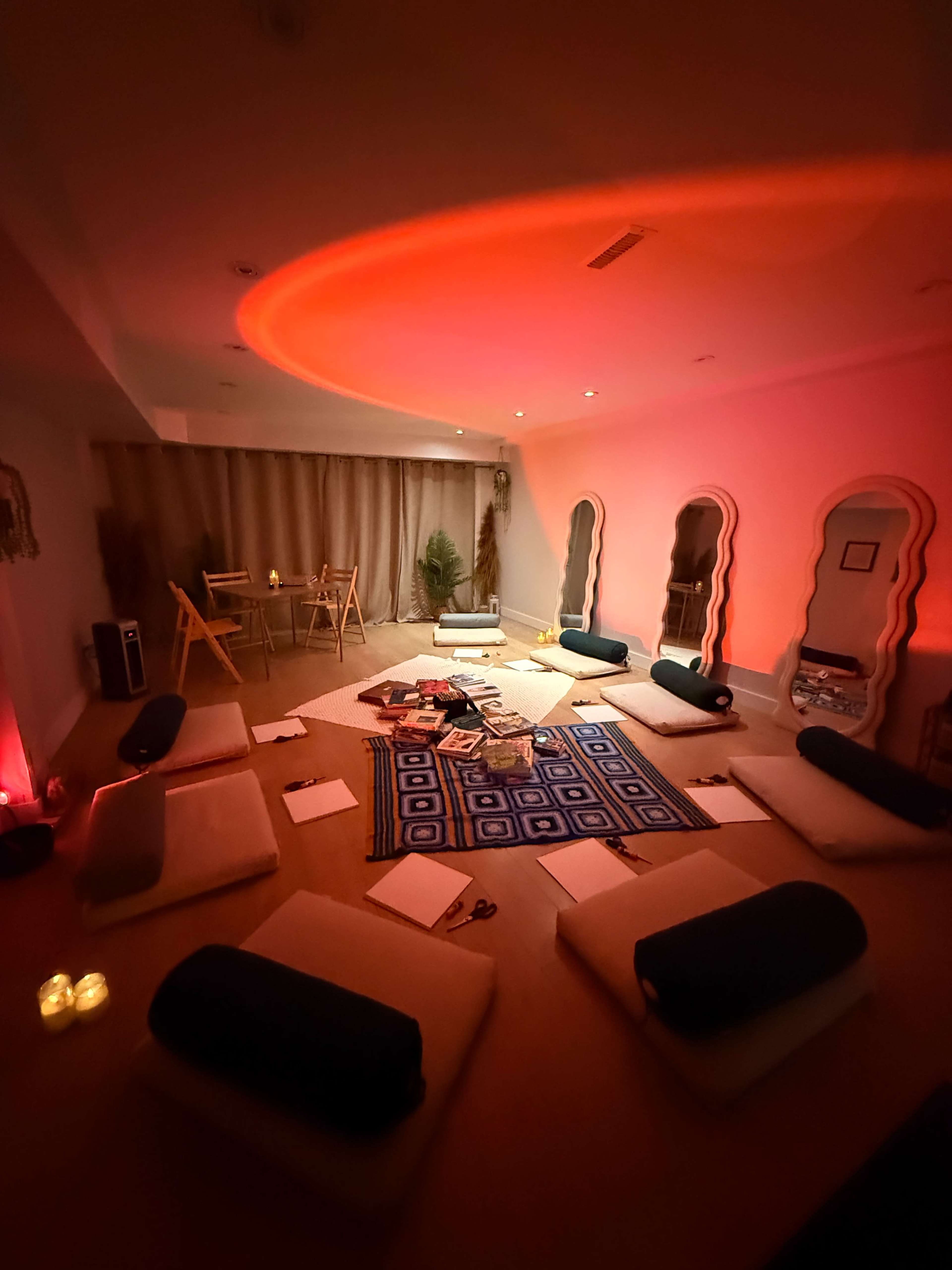 A meditation or wellness space features floor cushions arranged around a central rug, with soft lighting creating a warm ambiance.