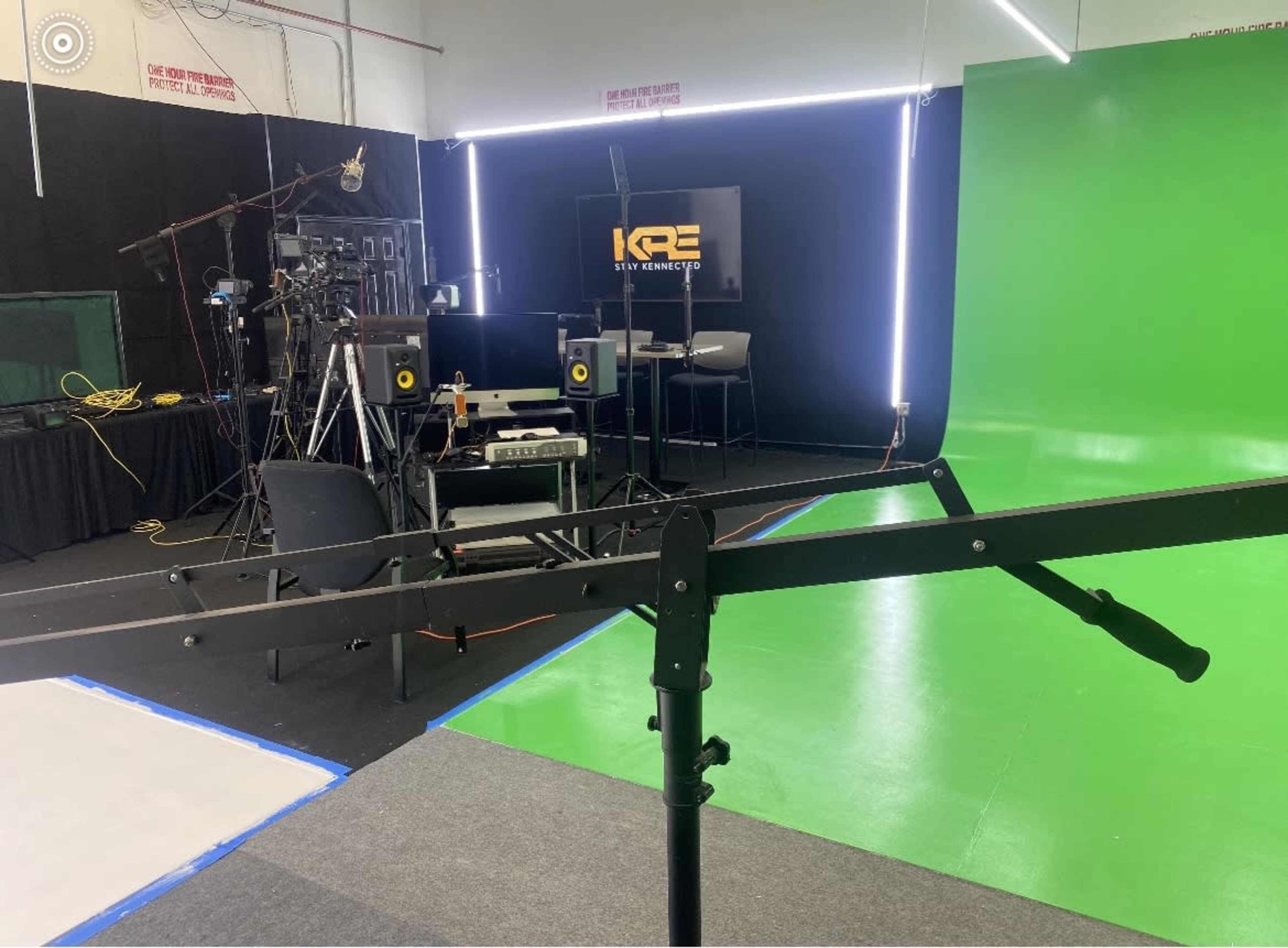 A studio setup featuring a green screen, cameras, lighting equipment, and a computer workstation.