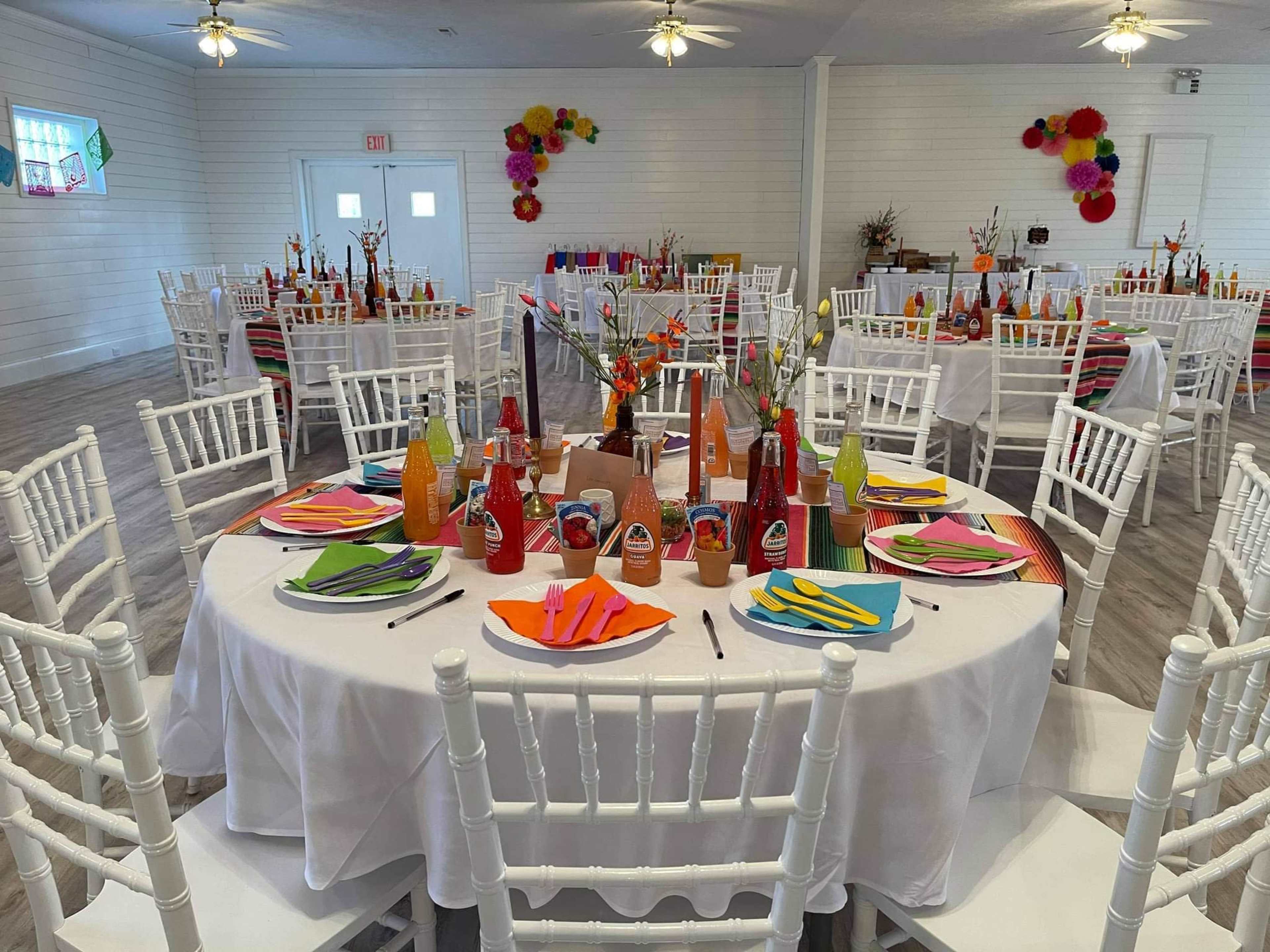 A decorated dining hall with multiple circular tables set with colorful tableware and soda bottles arranged neatly.