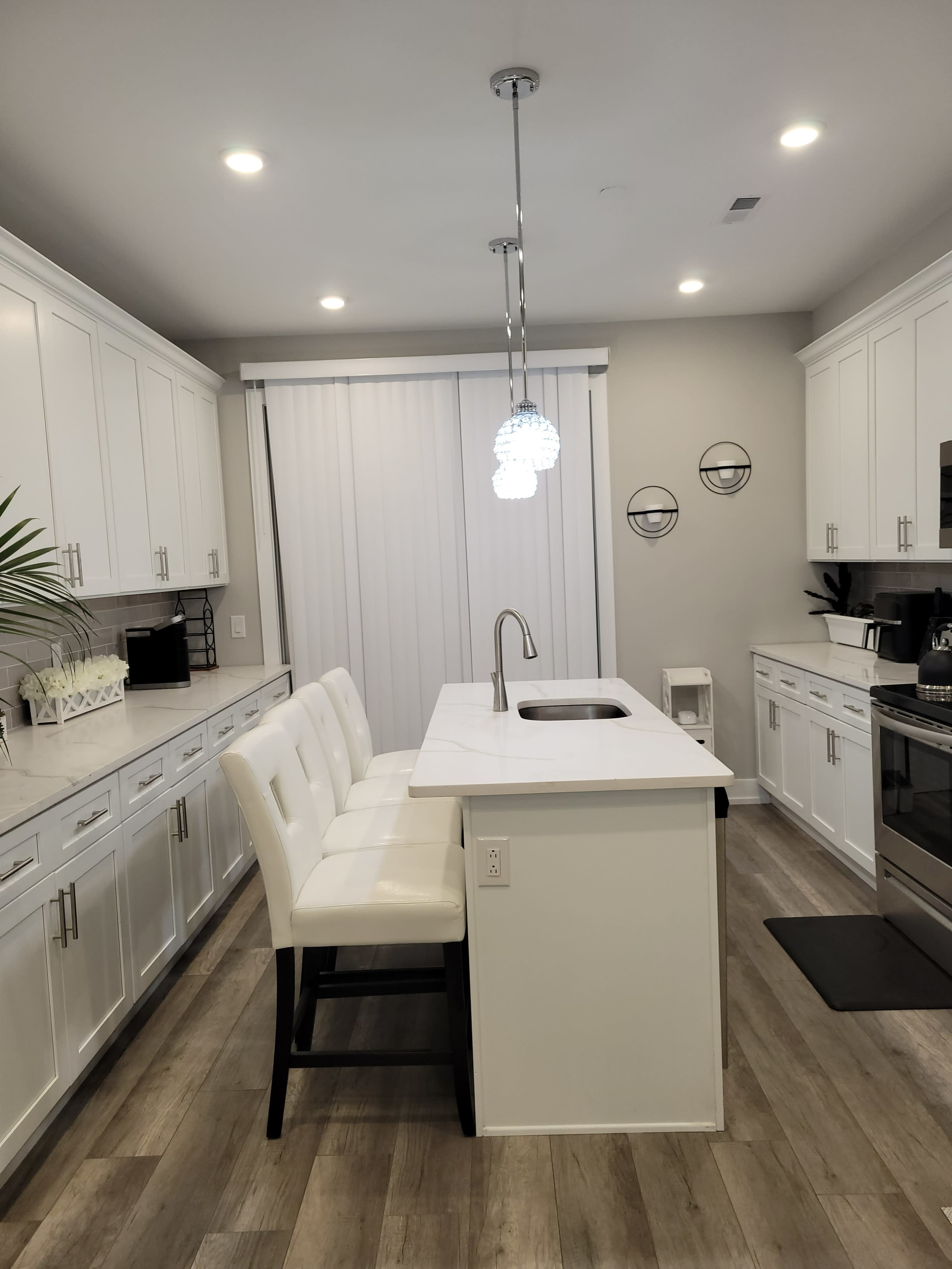 A modern kitchen with white cabinetry and a central island featuring bar seating and a sink.