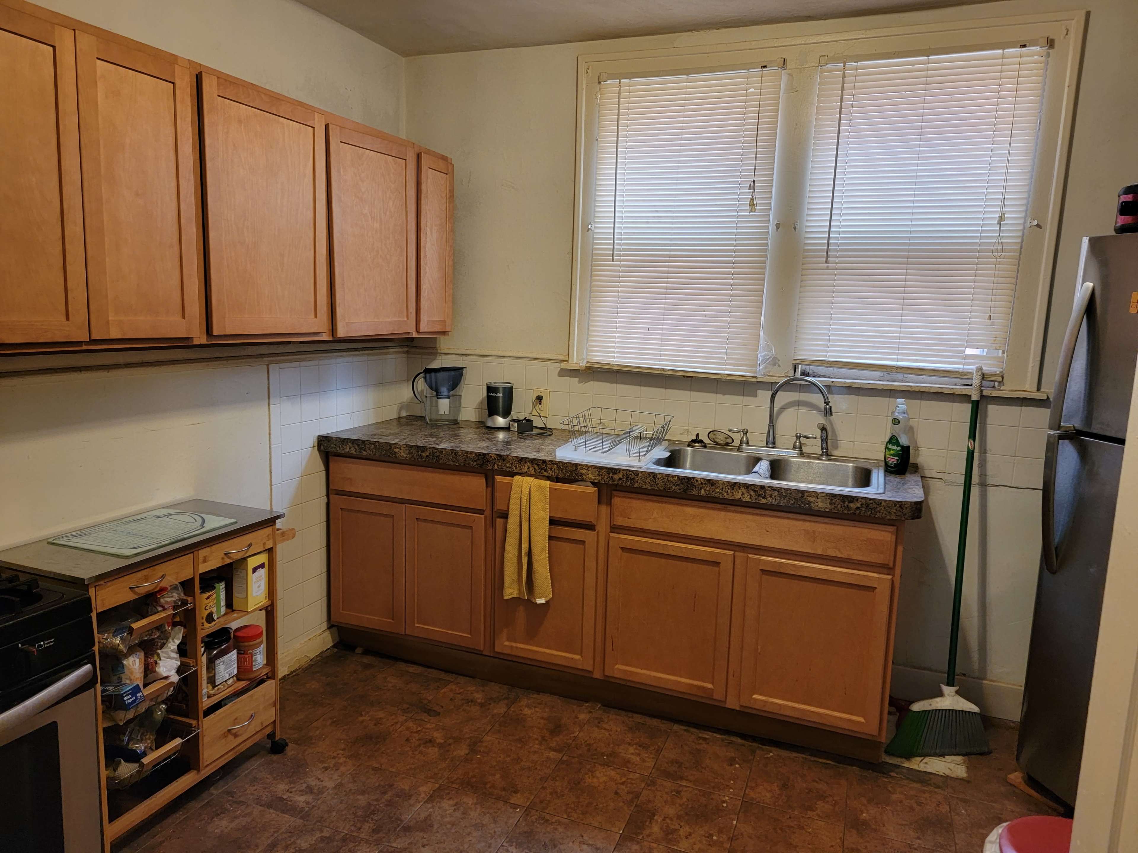 A small kitchen with wooden cabinets, a double sink, and appliances including a stove and refrigerator.