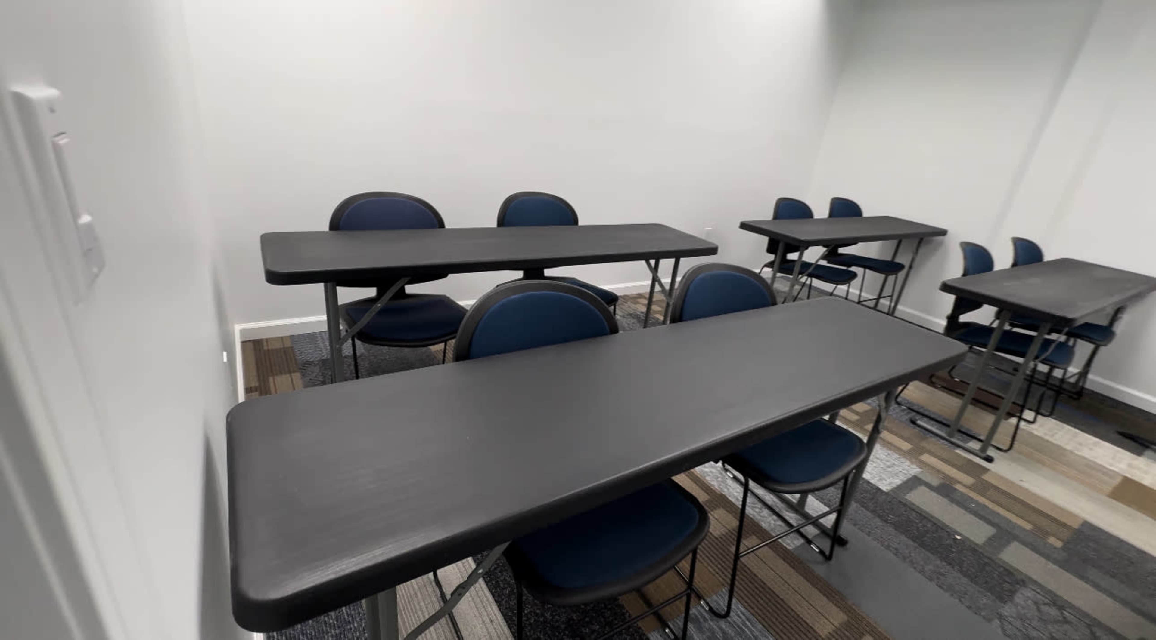 A room with several black tables and blue chairs arranged neatly.