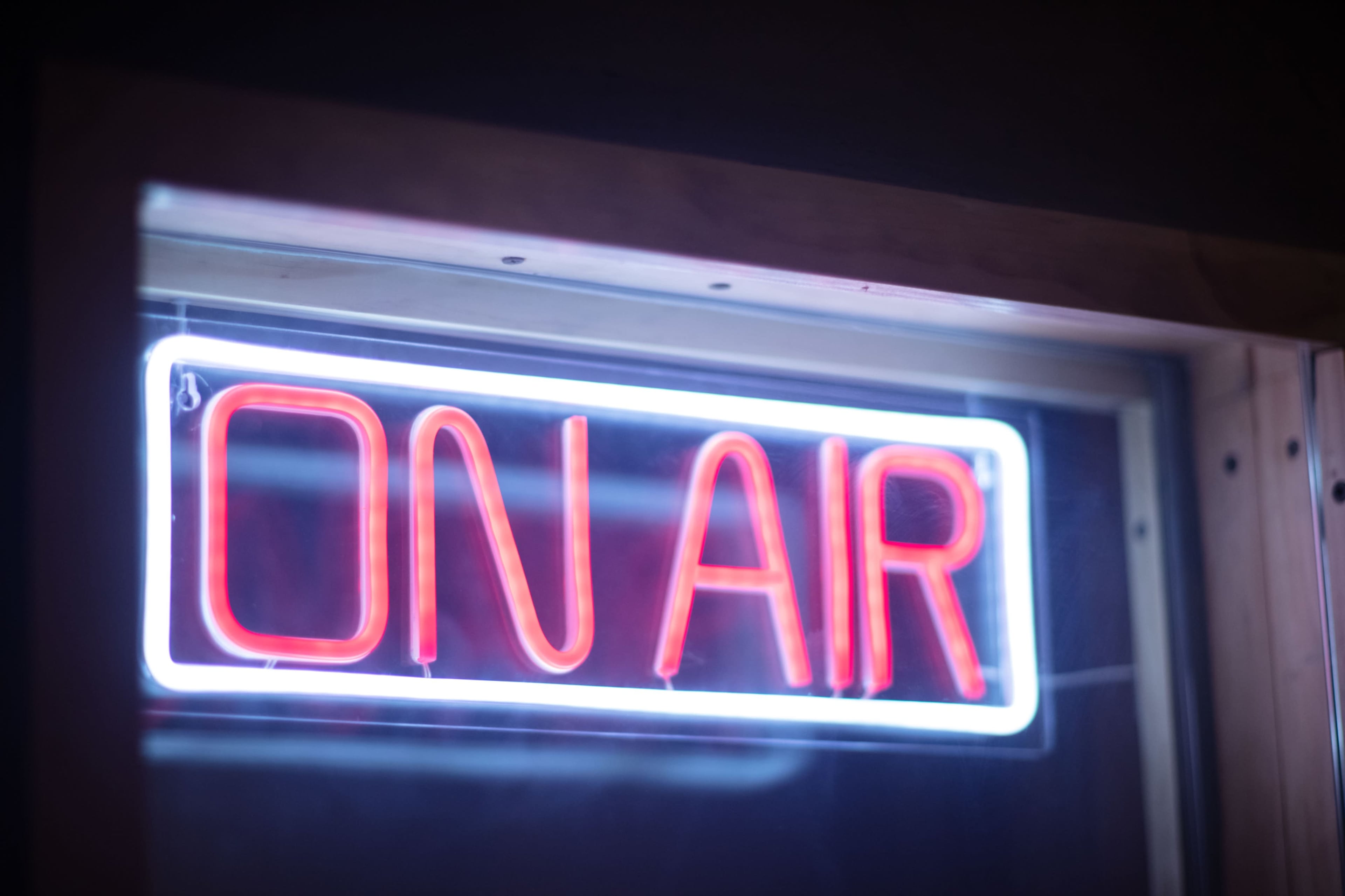 A glowing neon sign reading "ON AIR" illuminates a dimly lit space.