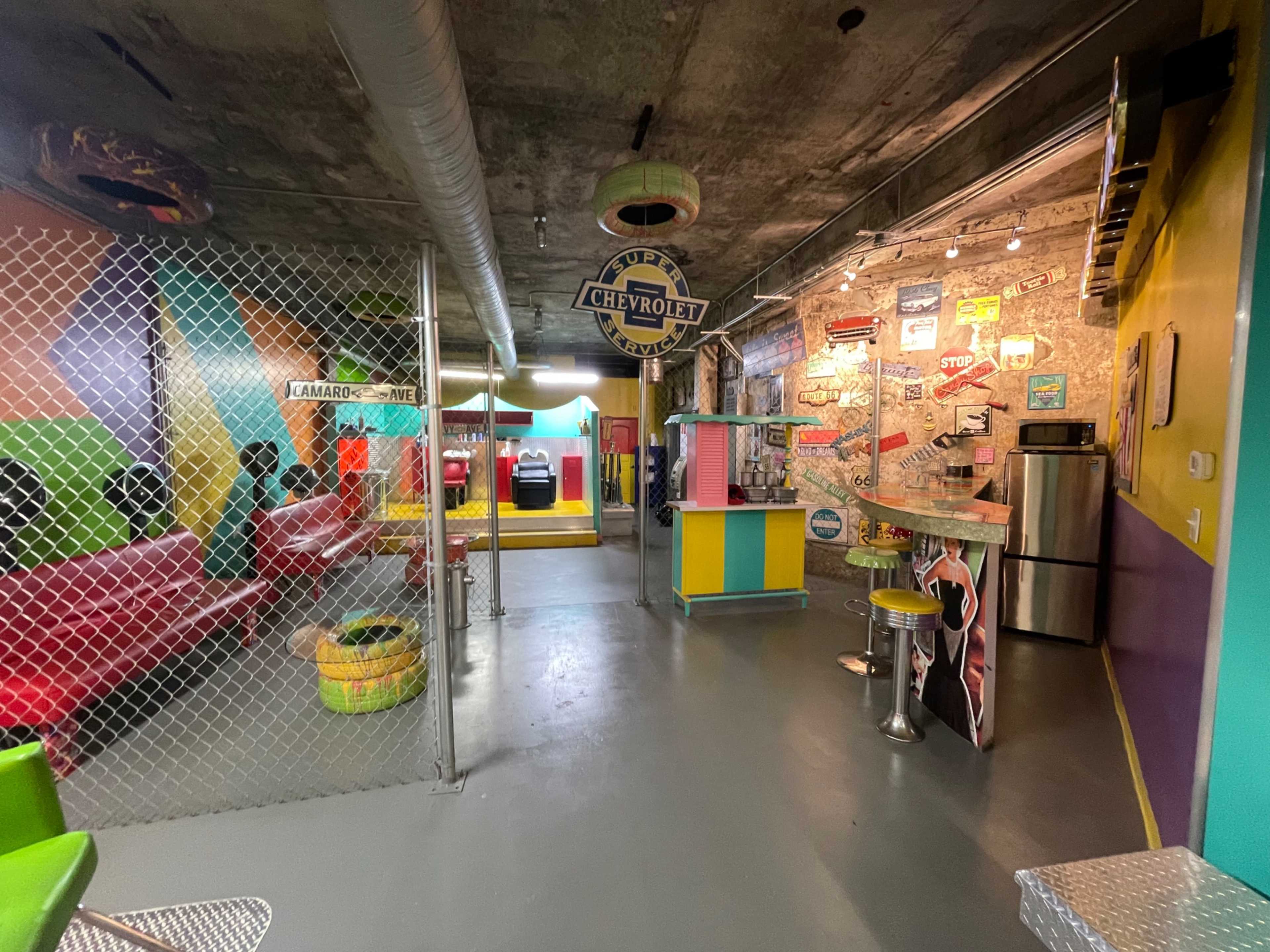 A colorful retro-themed diner interior with checkered walls, a bar area, and vintage signs.