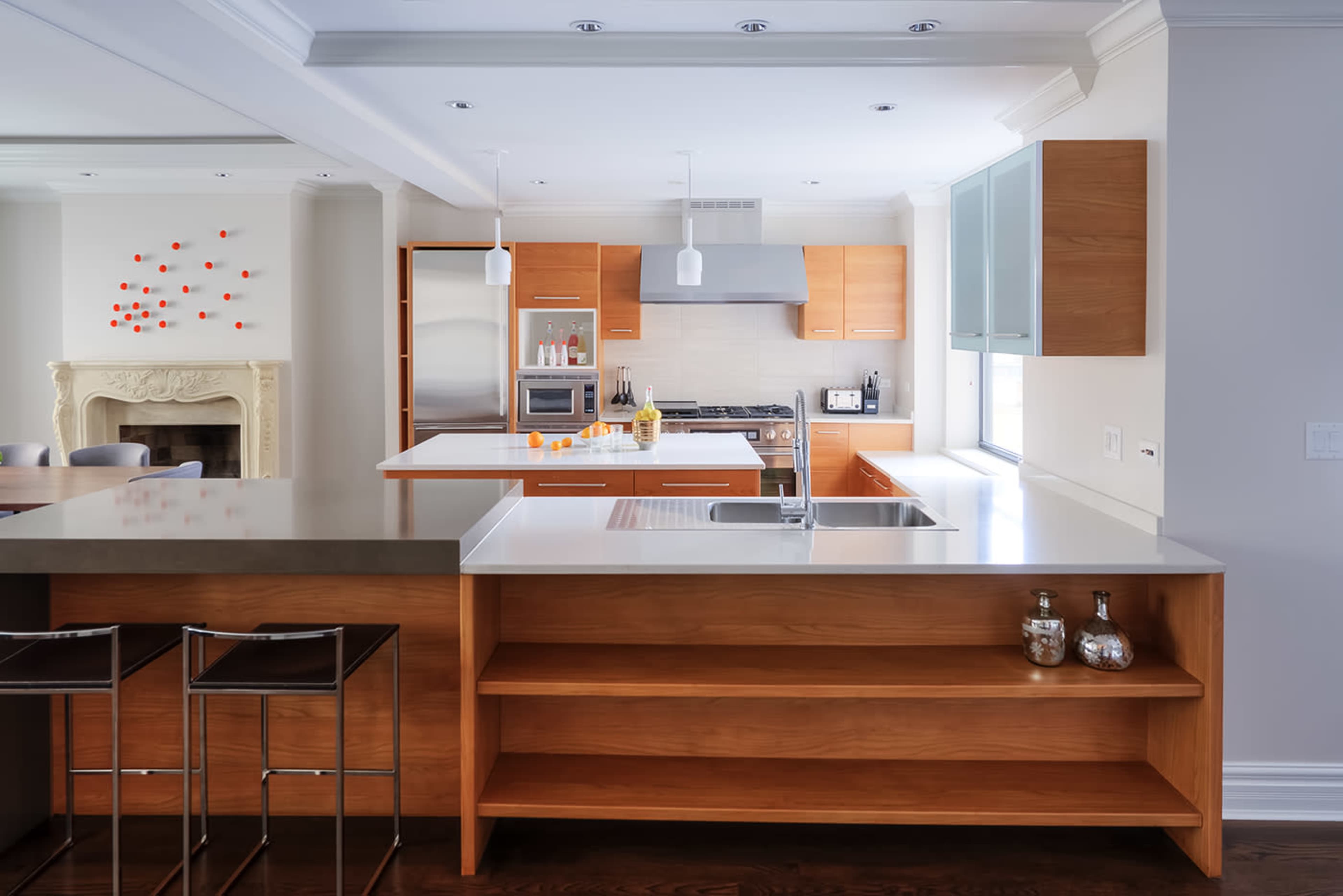 A modern kitchen featuring wooden cabinetry, a central island with a sink, and a stainless steel range hood above a gas stove.