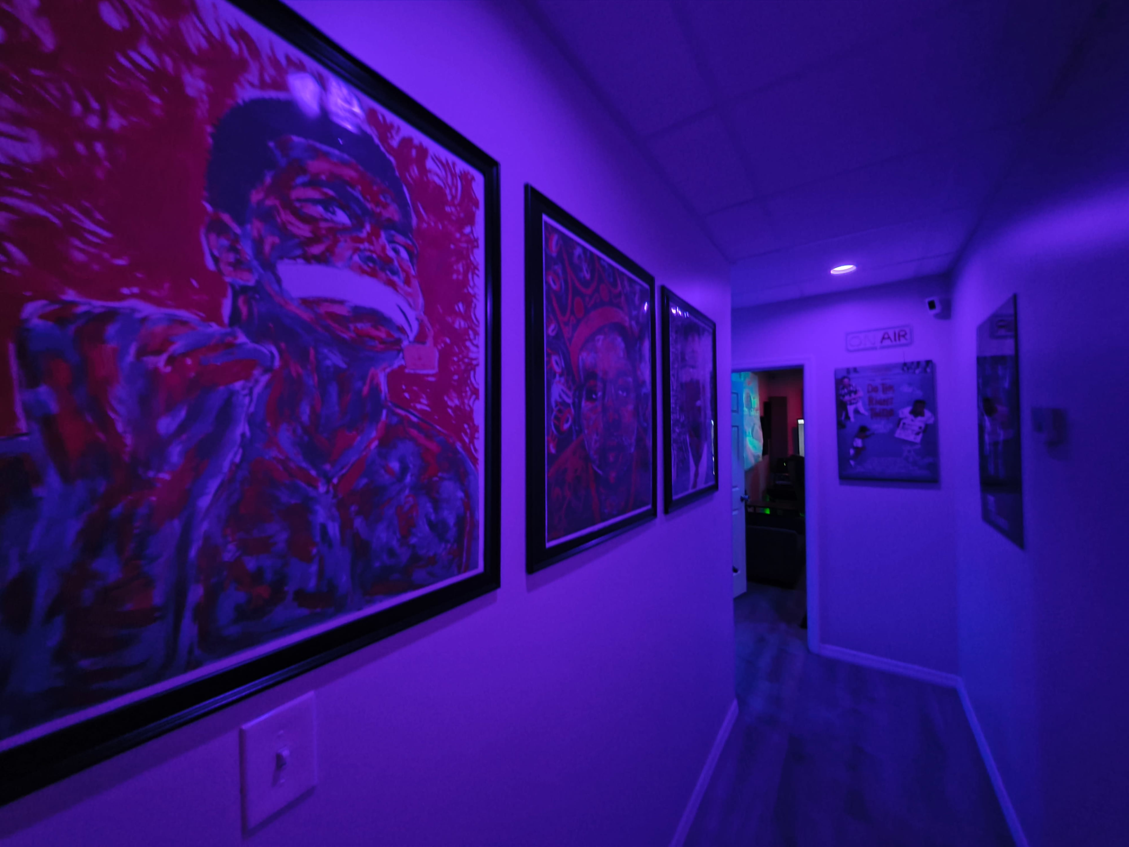 The corridor features vibrant artworks framed on the walls, illuminated by purple lighting.