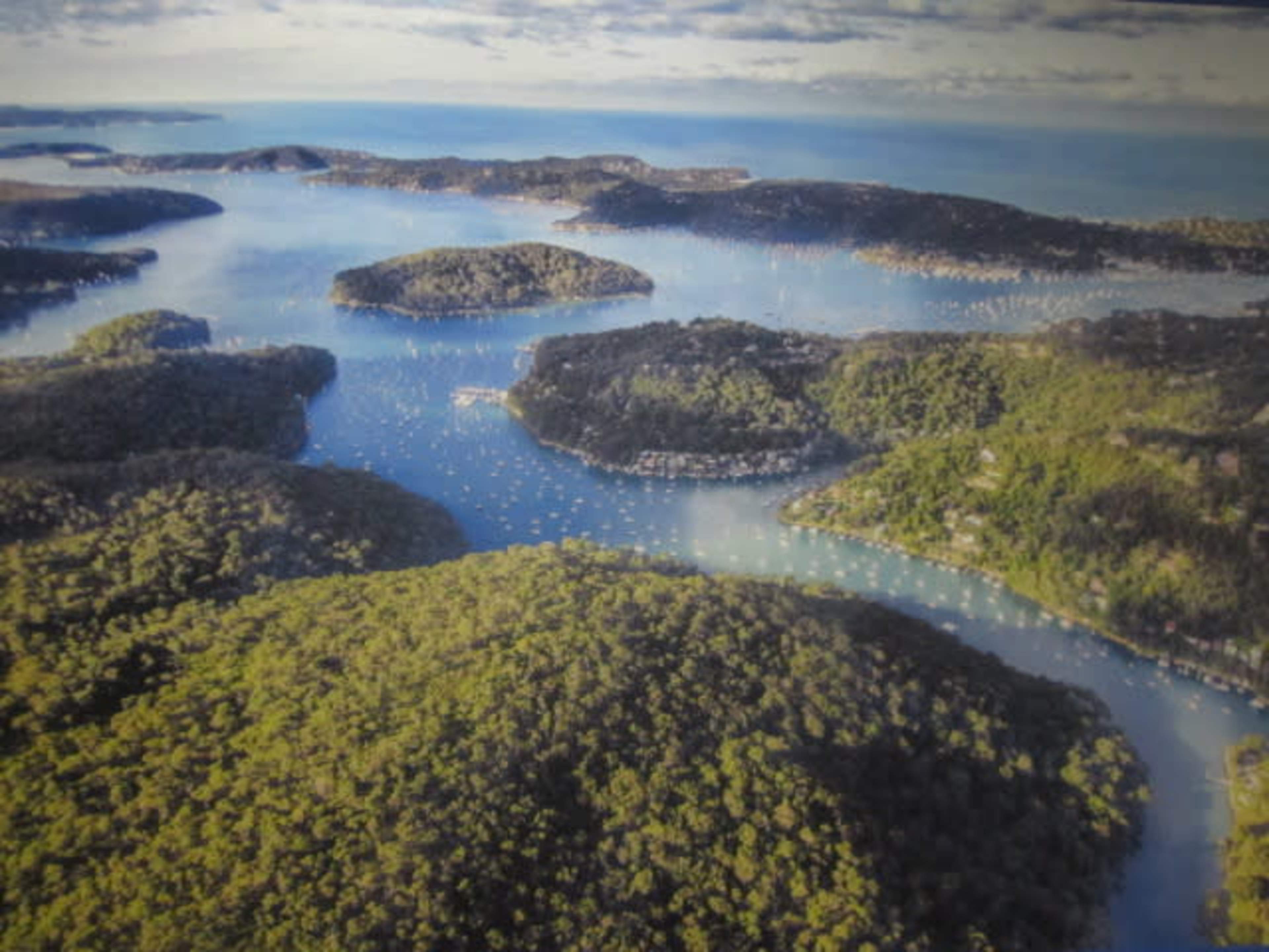 The image shows a bird's-eye view of a coastal landscape featuring numerous islands and bays surrounded by lush greenery and blue waters.
