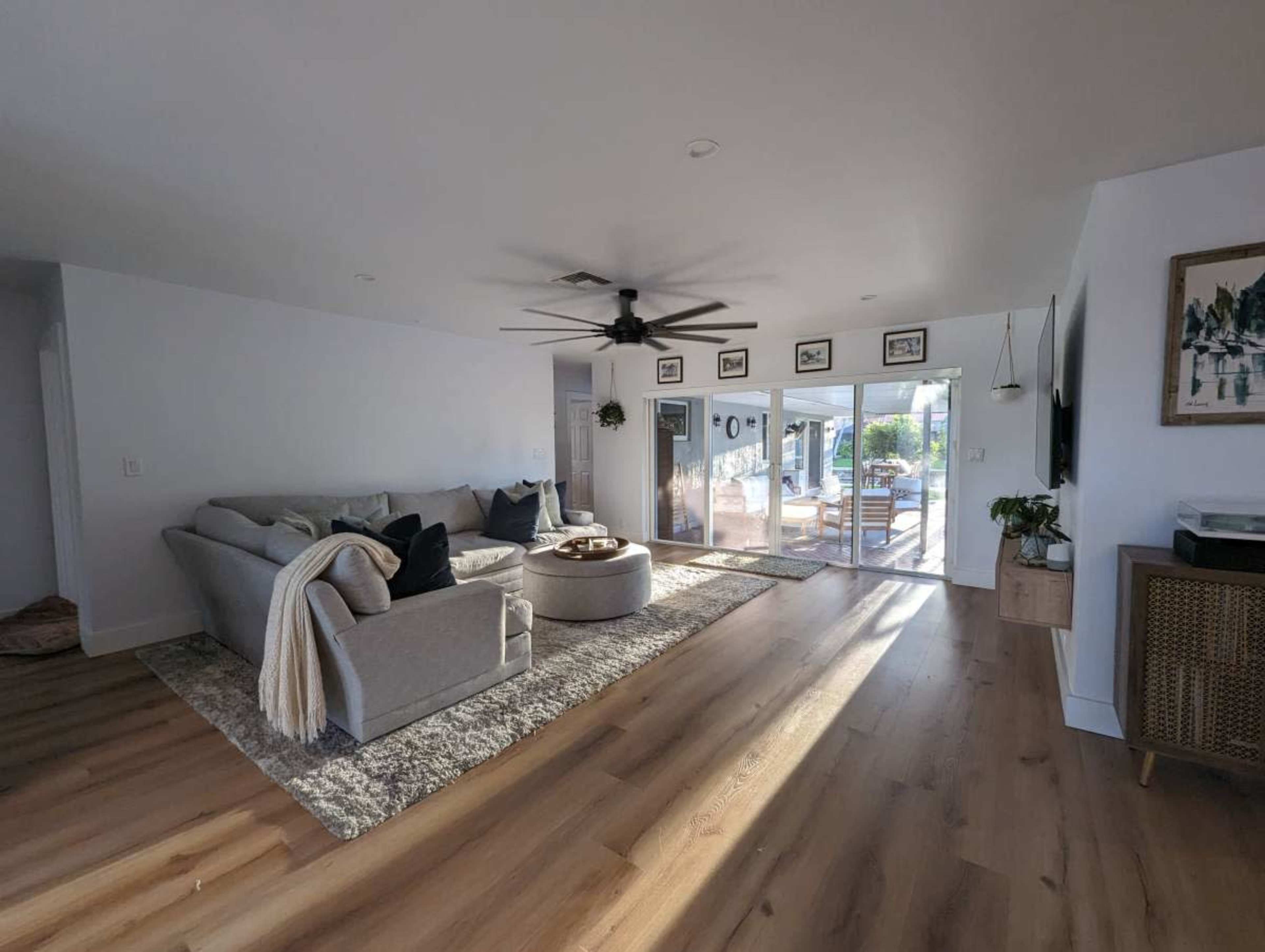 A spacious living room features a gray sectional sofa, a round coffee table, and large sliding doors that open to a patio area.