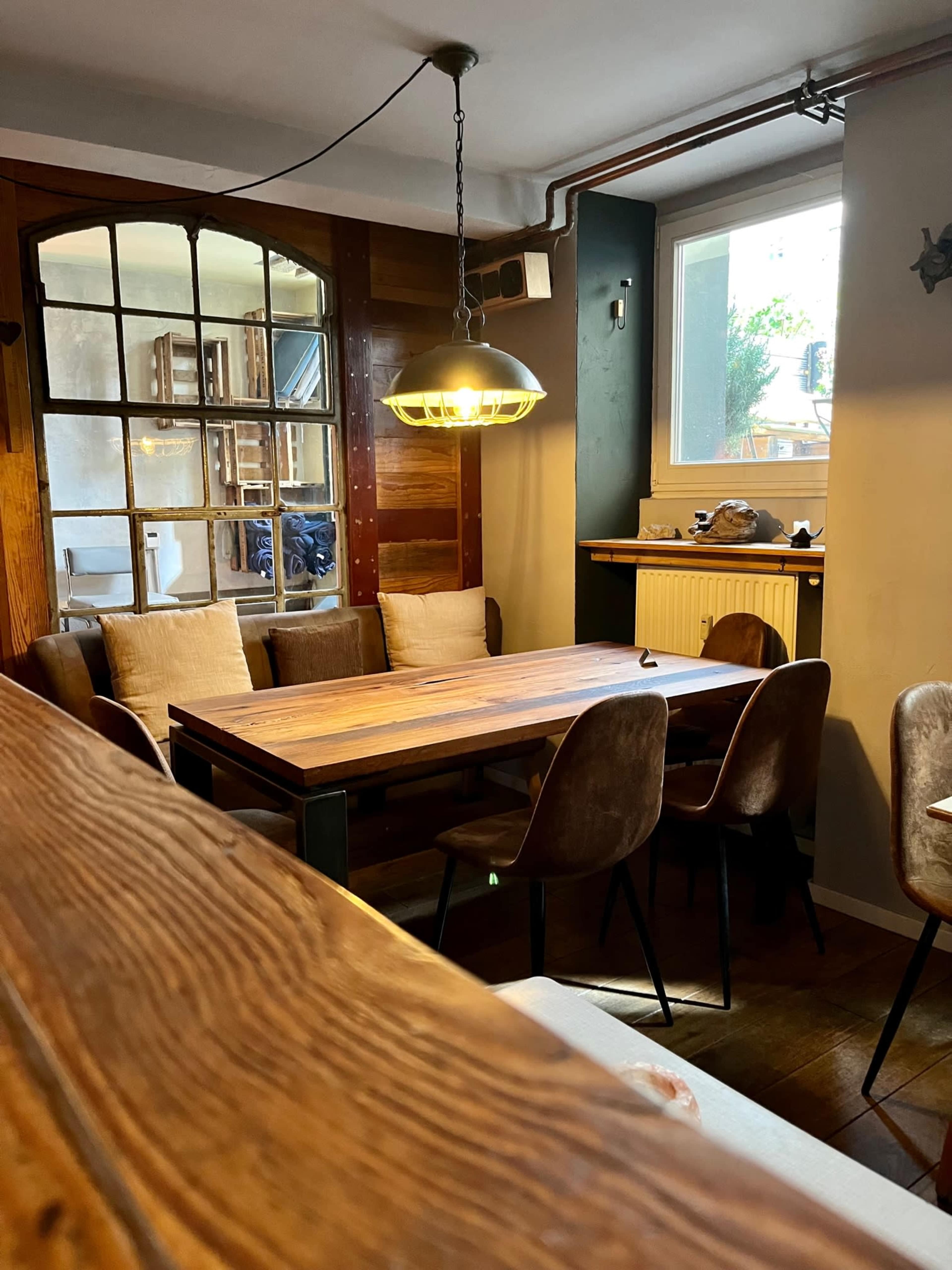 A cozy dining area with a wooden table, several chairs, and a large window letting in natural light.