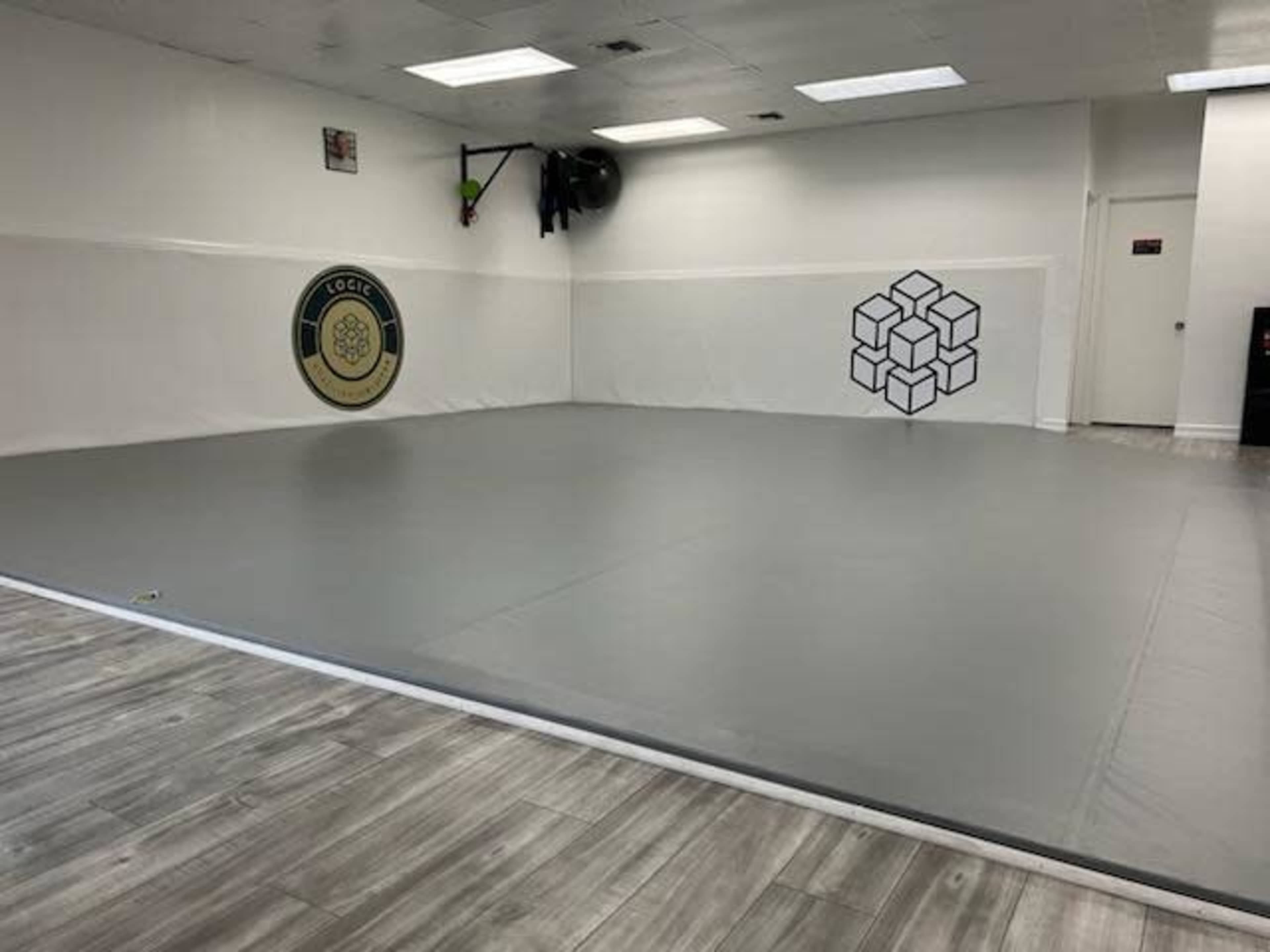 A sparsely decorated training room with gray mats and wall decals on two sides.