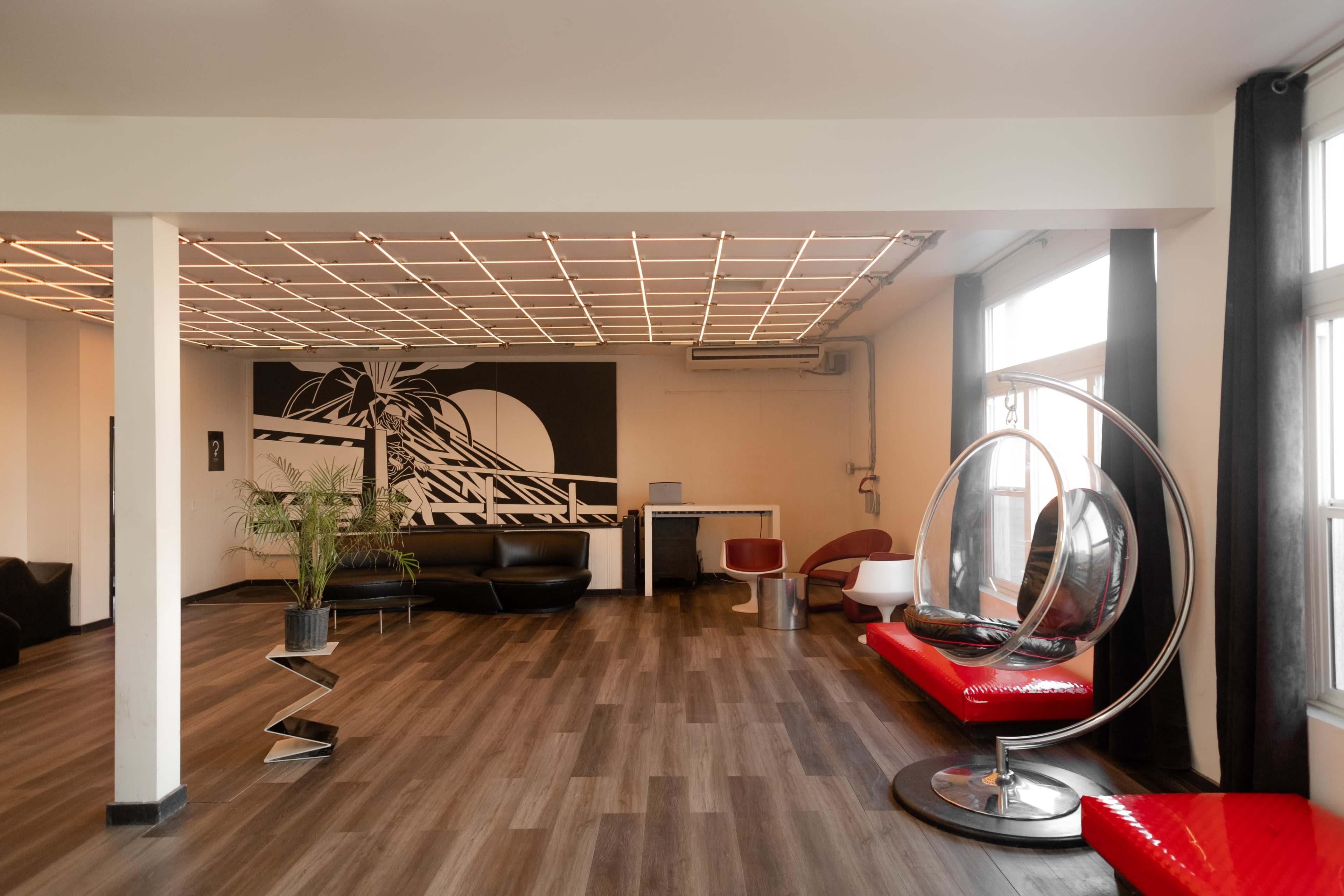 A spacious modern lounge with stylish seating, a black and white mural on the wall, and a large window allowing natural light.