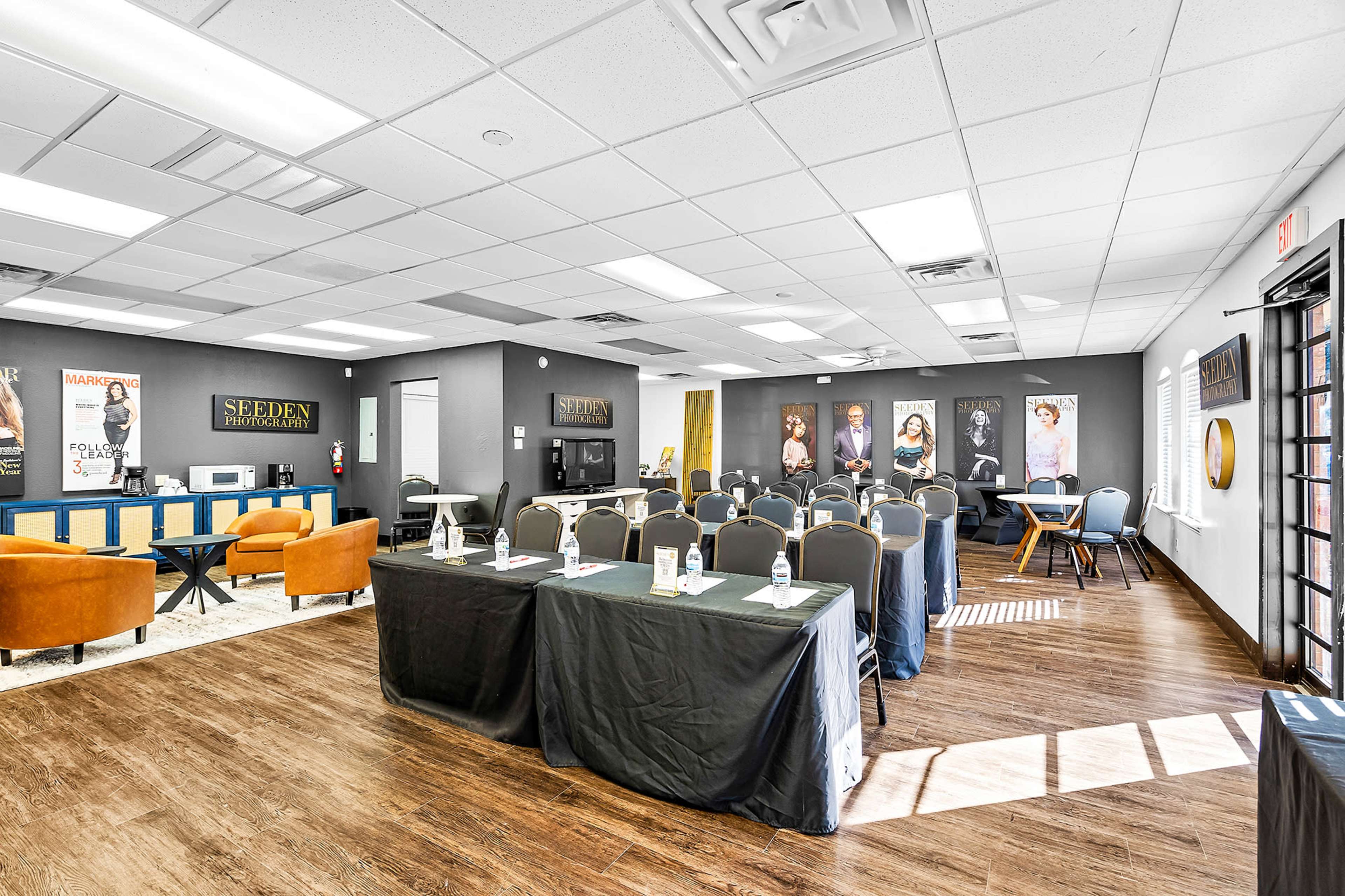 A modern conference room set up for a meeting, featuring tables with black linens, chairs, and framed artwork on the walls.