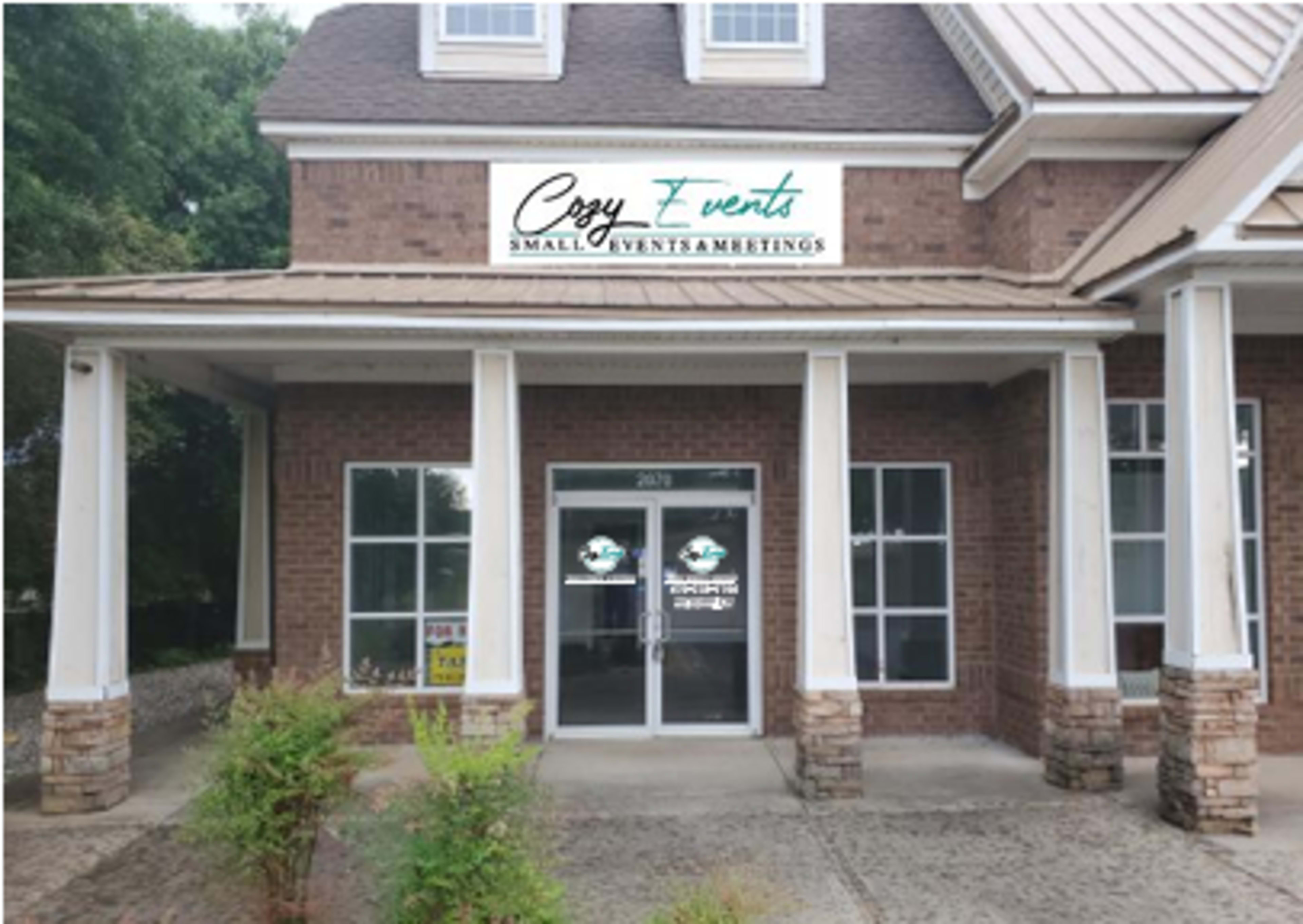 The image shows a brick building featuring a sign for "Cozy Events" above the entrance, indicating it hosts small events and meetings.