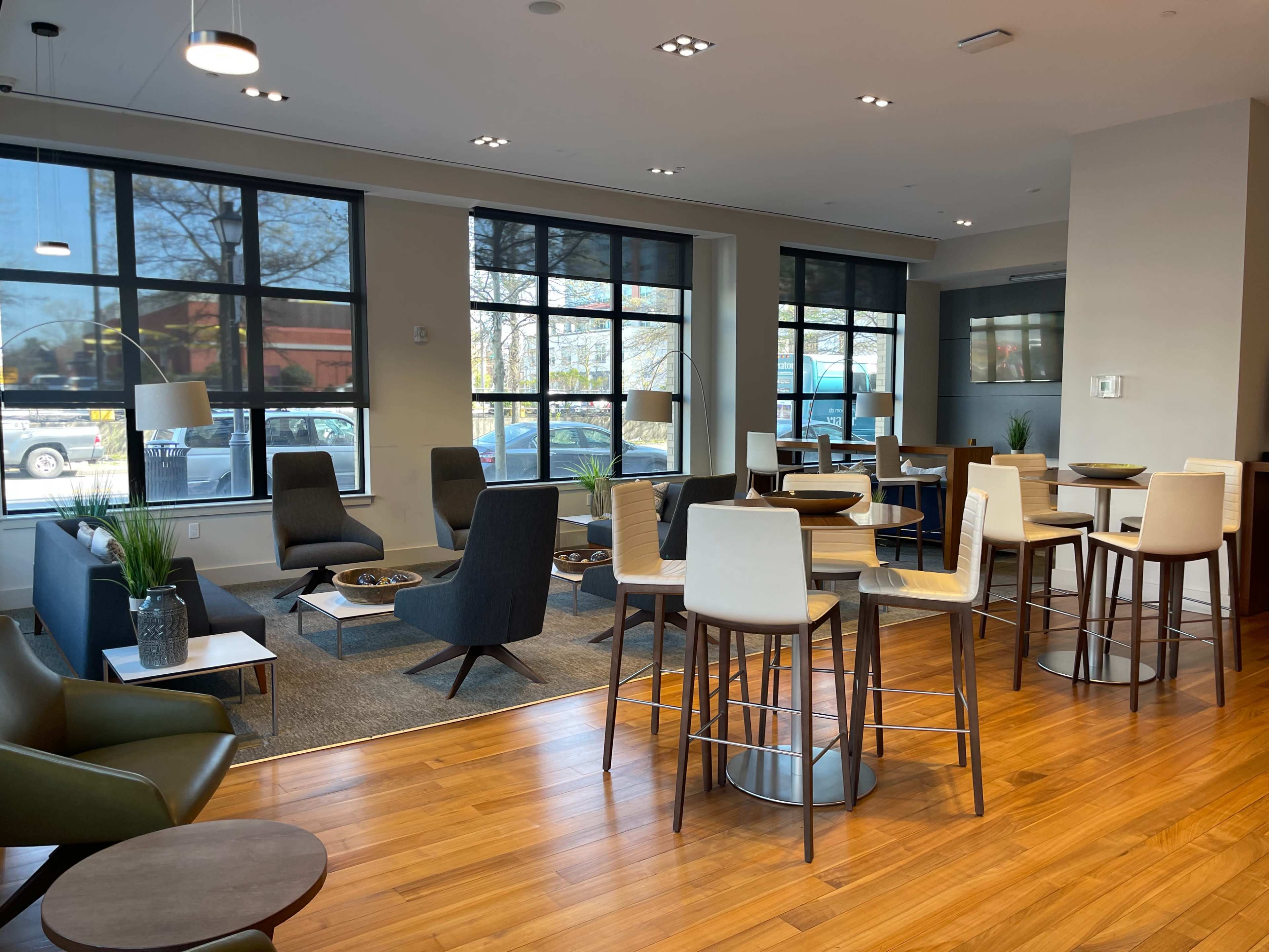 A spacious lounge area furnished with modern seating, small tables, and large windows allowing natural light to enter.