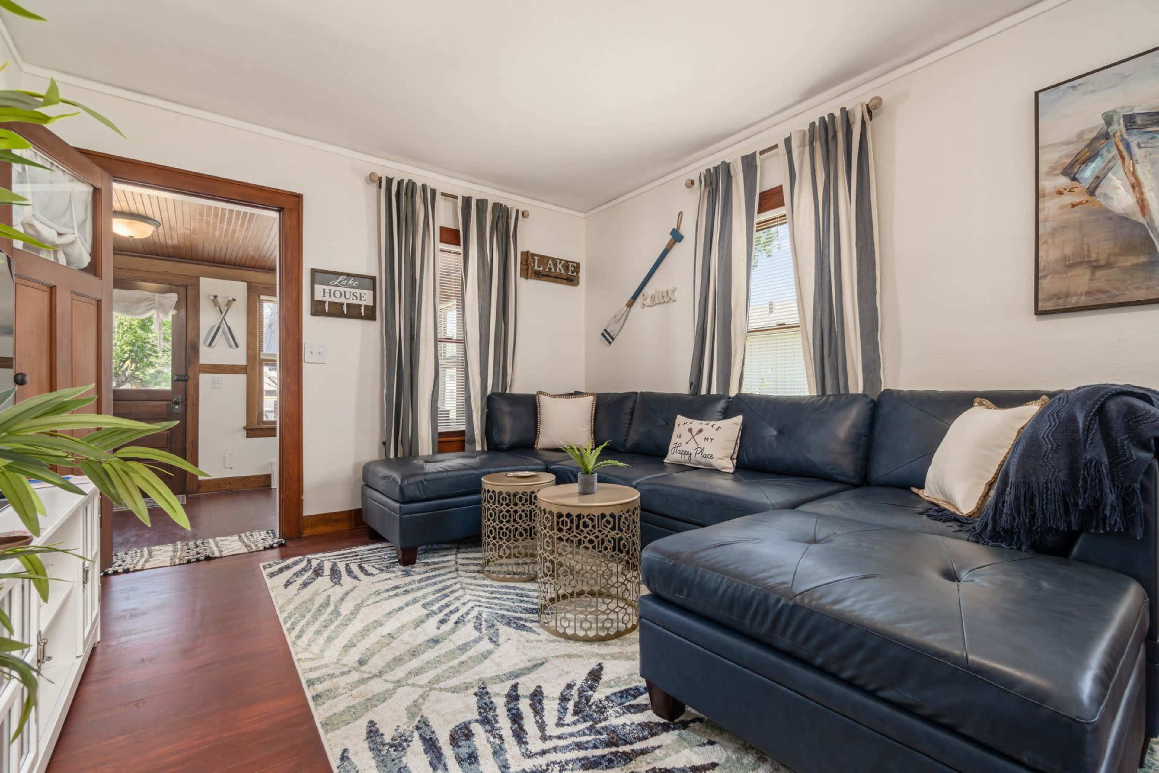A living room with a sectional sofa, a coffee table, and large windows dressed with curtains.