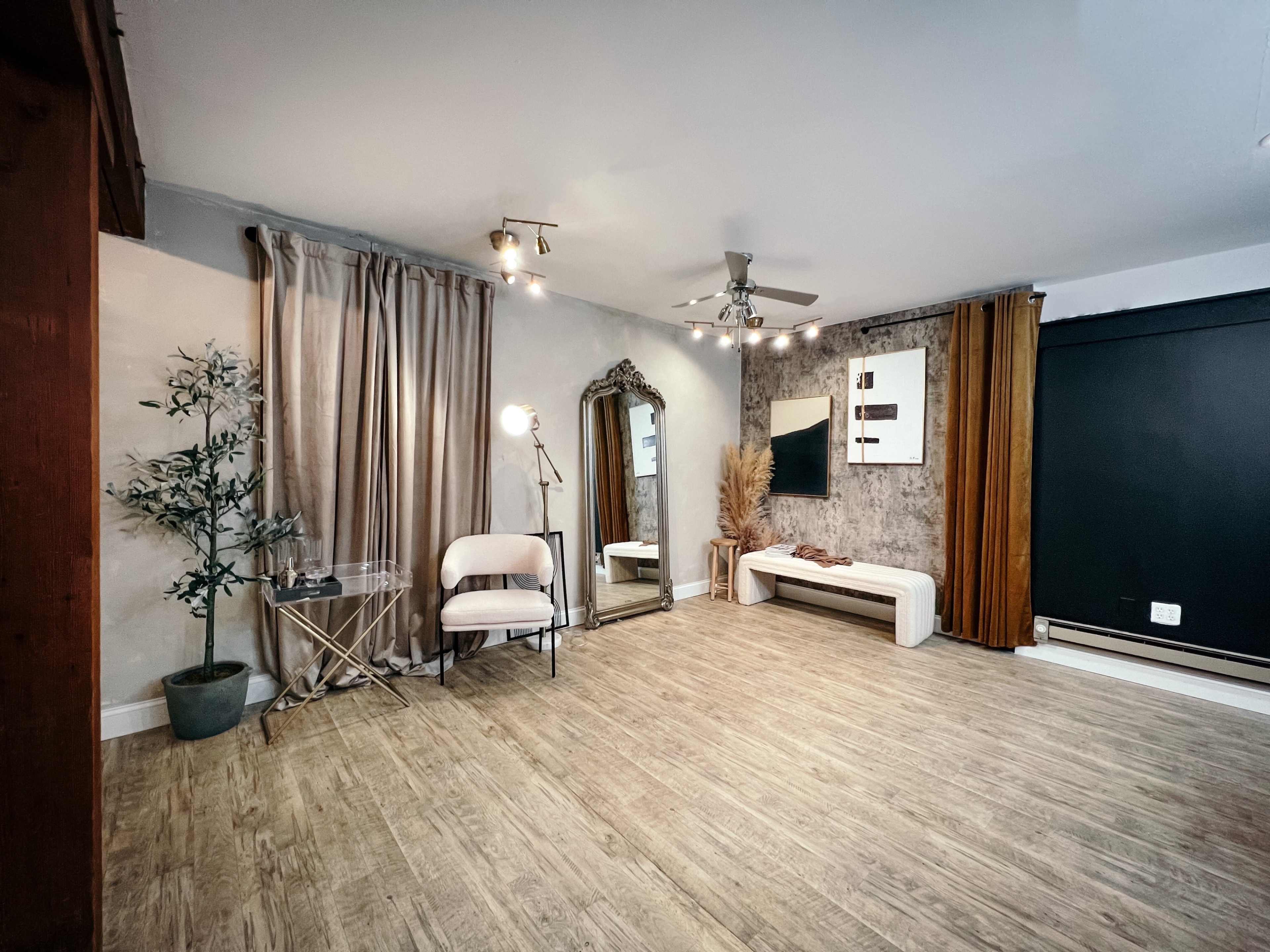 A modern interior space featuring a large mirror, a sleek bench, and decorative elements against a backdrop of curtains and wall art.