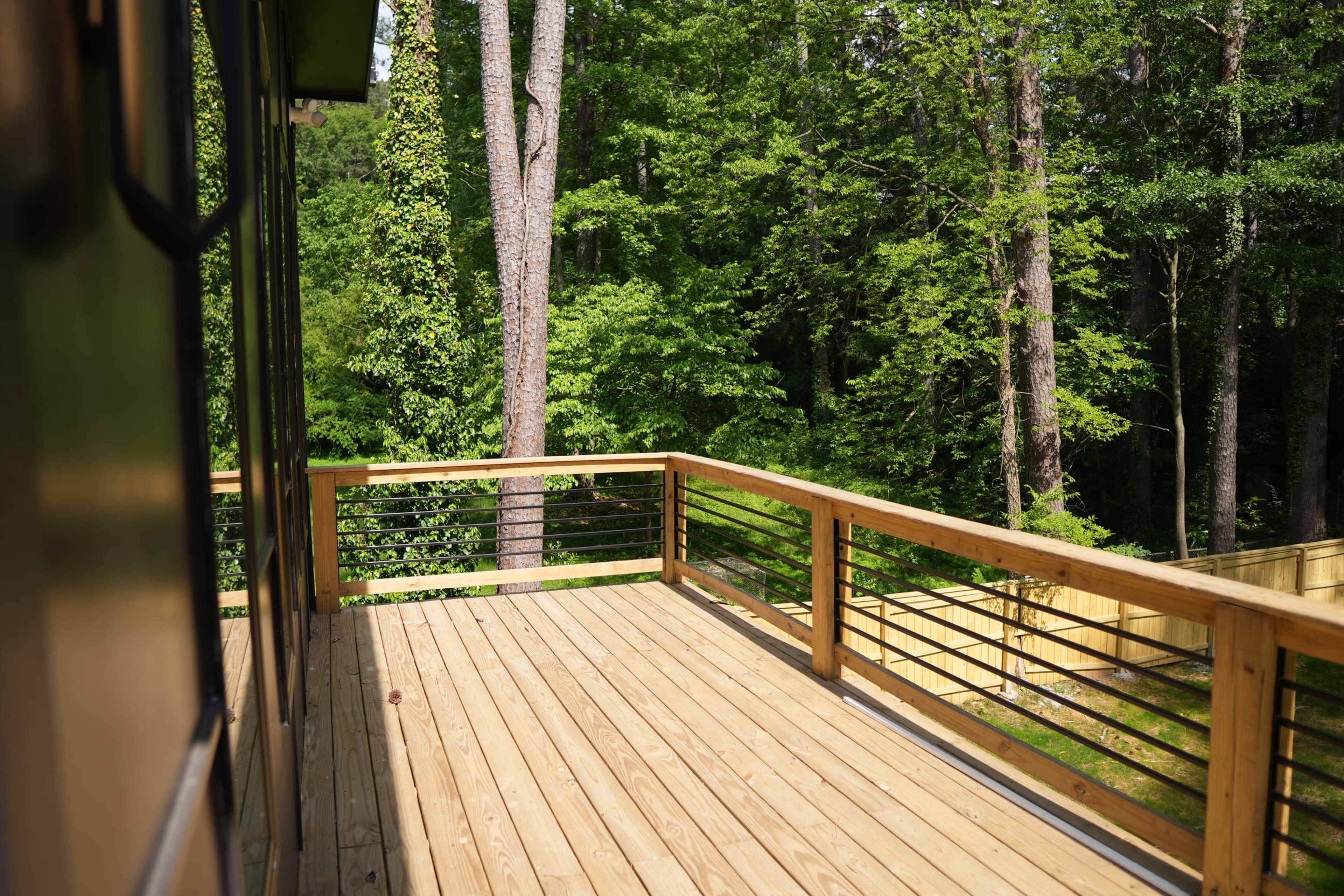 A wooden deck extending into a wooded area with trees in the background.