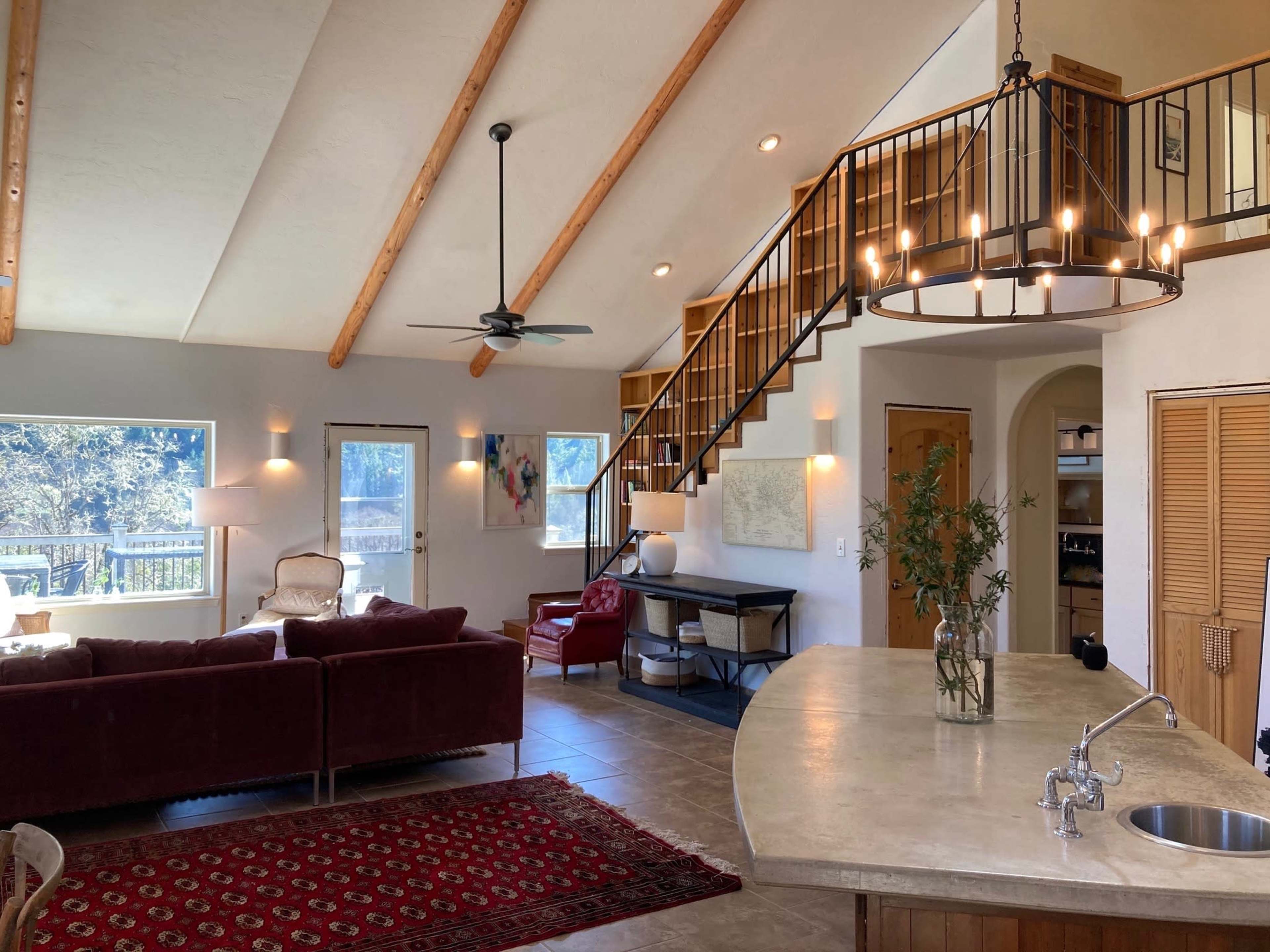 An open-concept living area with high ceilings, a staircase, and a kitchen island in a modern home.