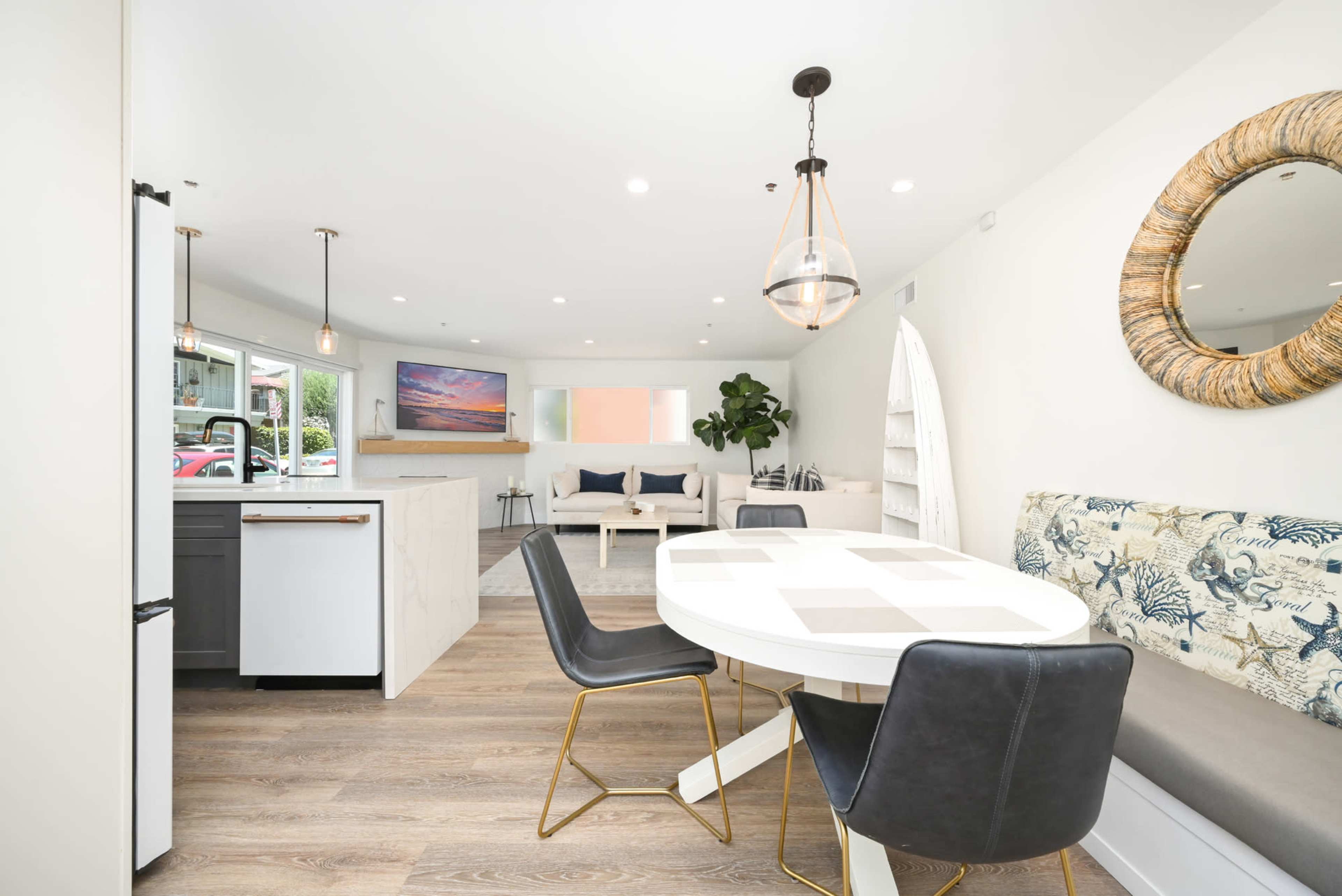 A modern living space features a dining area with a round table and chairs, a kitchen with a white countertop, and a cozy sitting area with a couch and decorative elements.