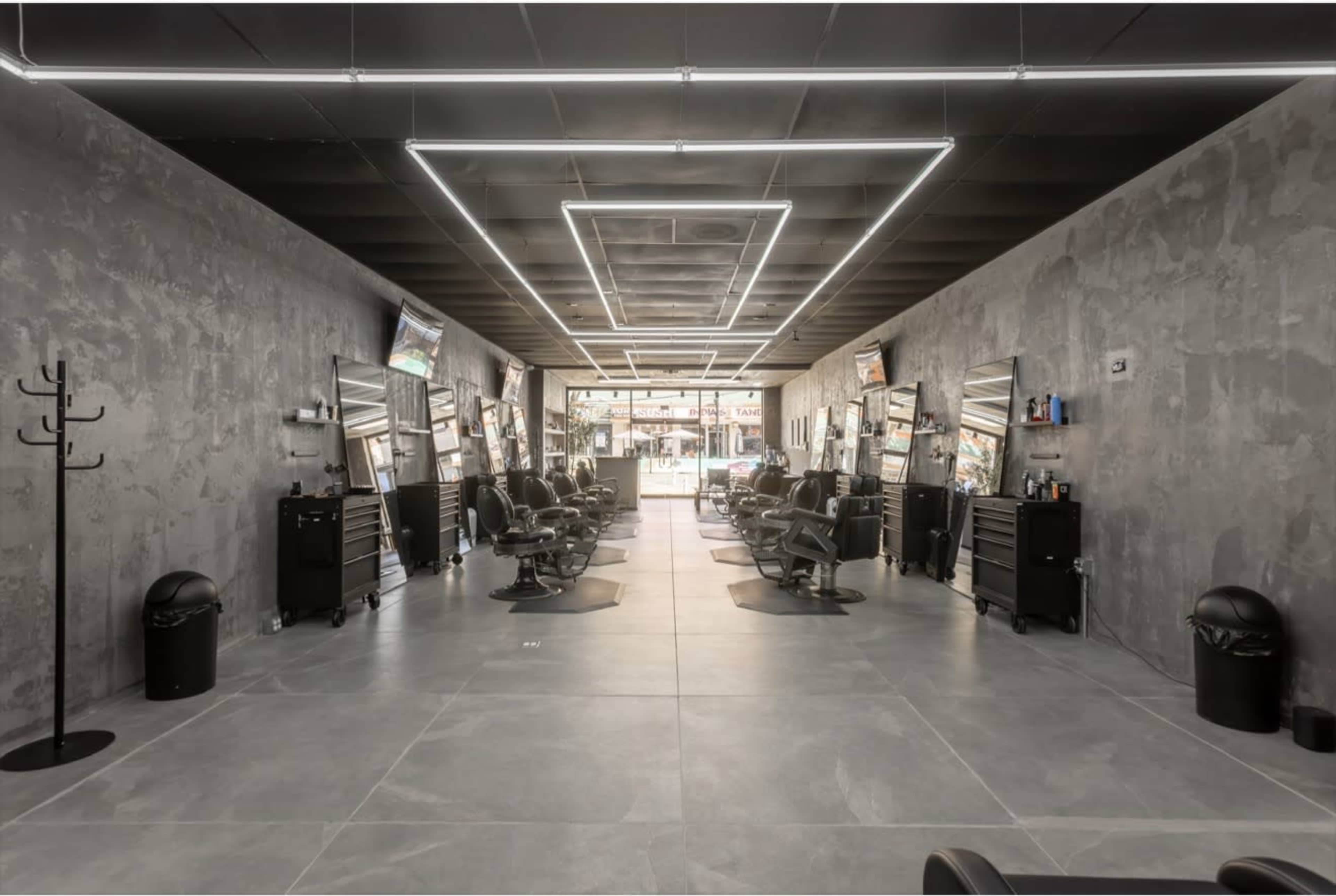 The image shows a modern hair salon interior with gray walls, multiple styling chairs, and bright LED lighting.