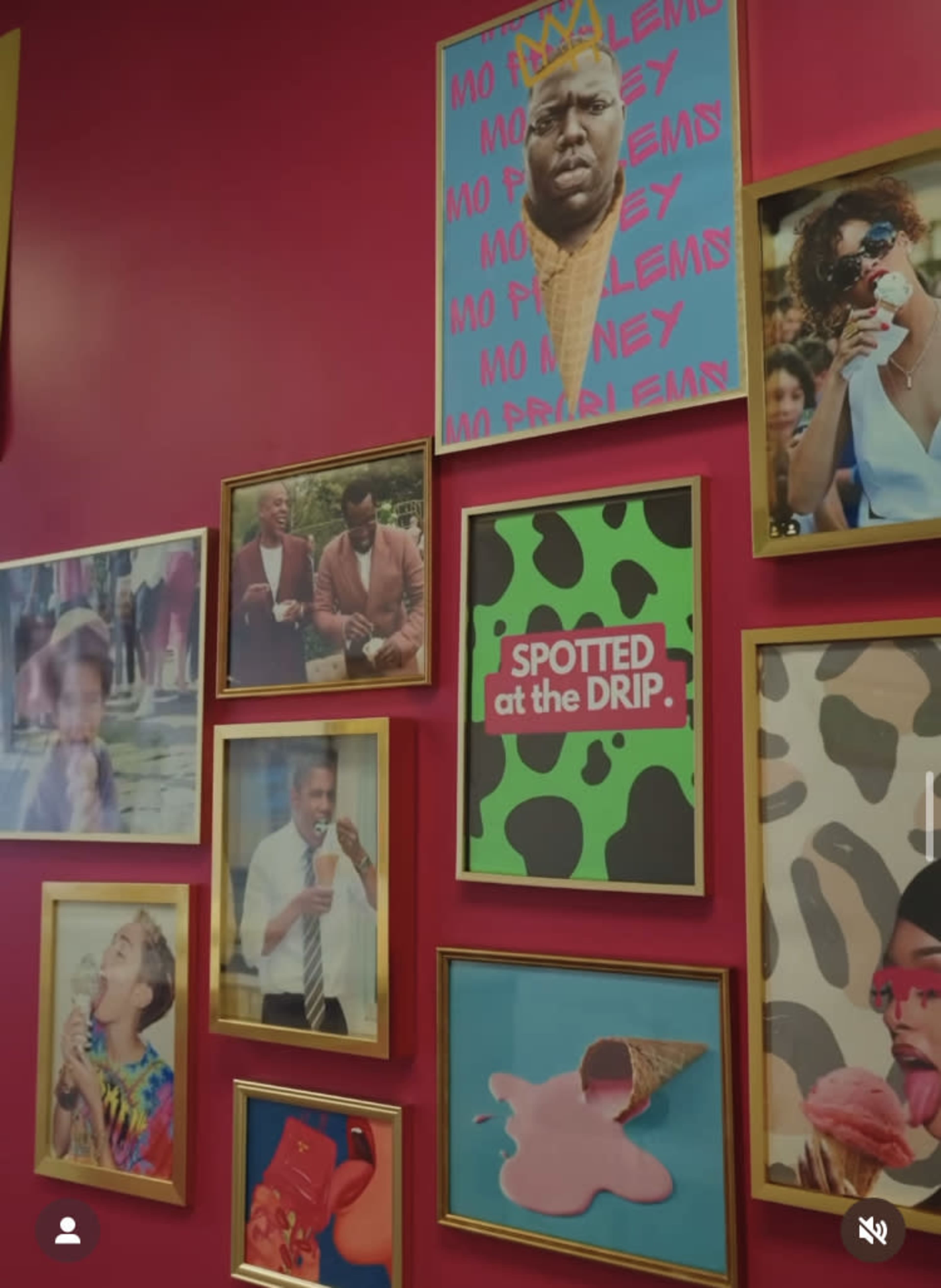 The image shows a wall adorned with various framed photos and artwork featuring people enjoying ice cream and playful graphic designs on a vibrant pink background.