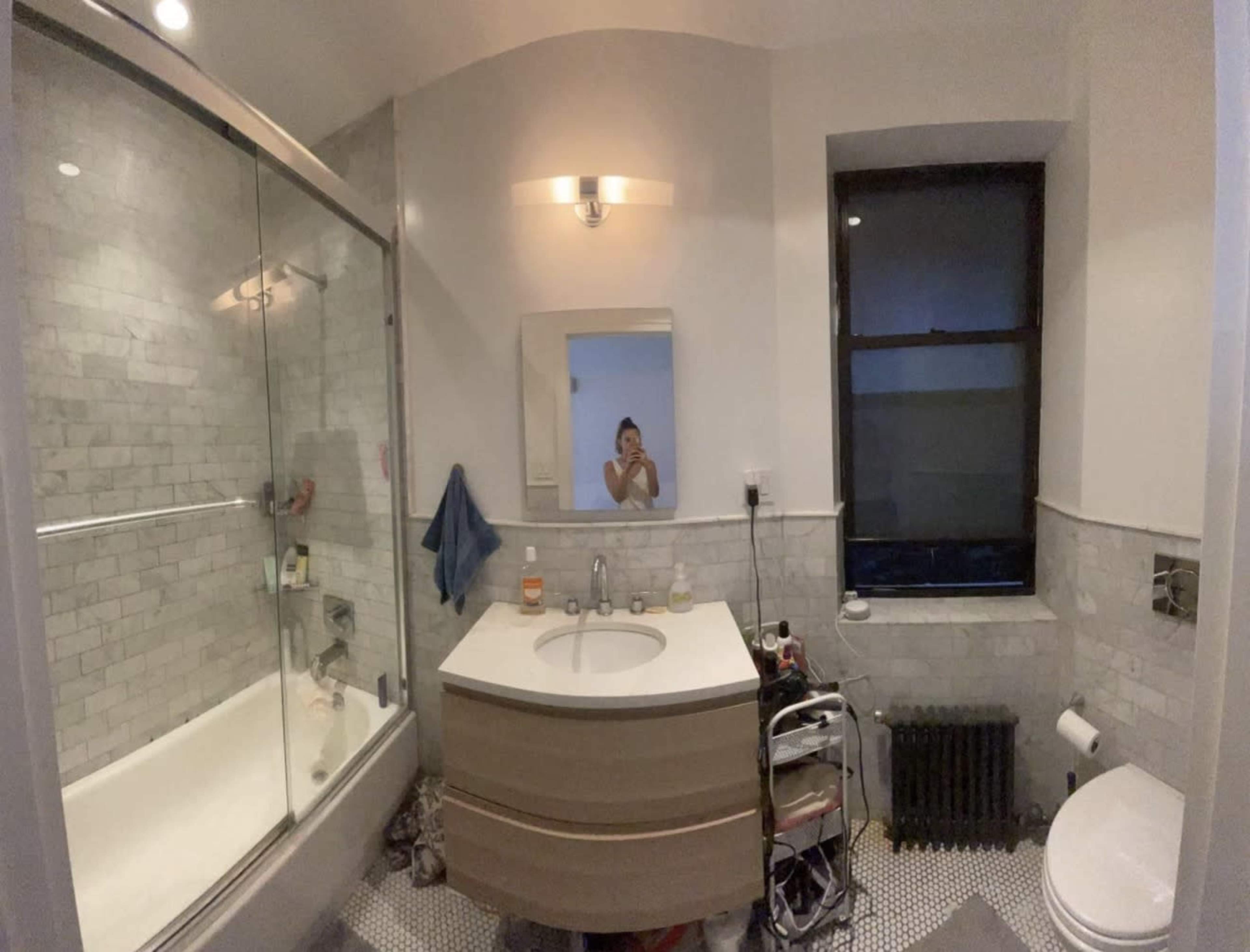 The image shows a modern bathroom featuring a glass shower, a freestanding sink with an oval shape, and a white toilet beside it.