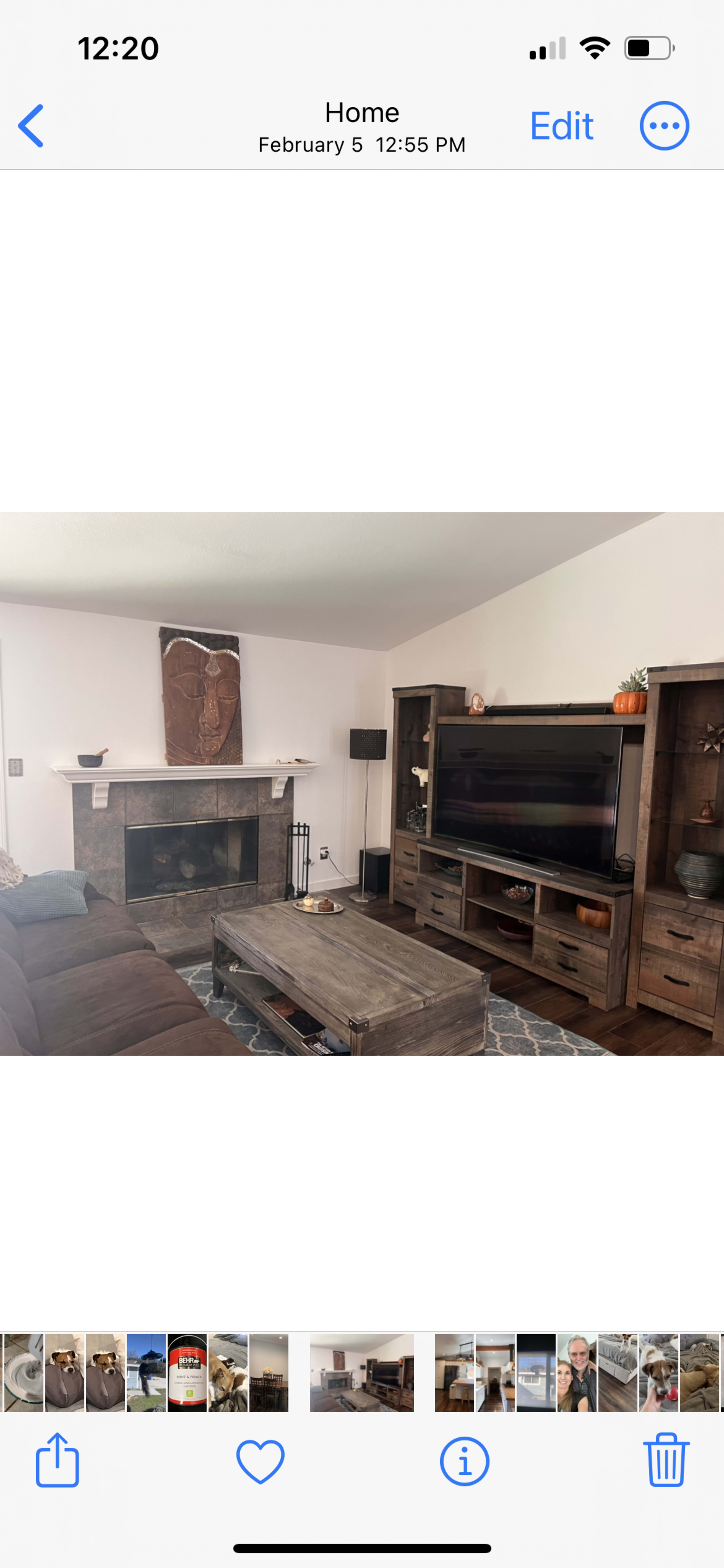 A living room featuring a brown sectional sofa, a wooden coffee table, a large TV cabinet, and a stone fireplace.