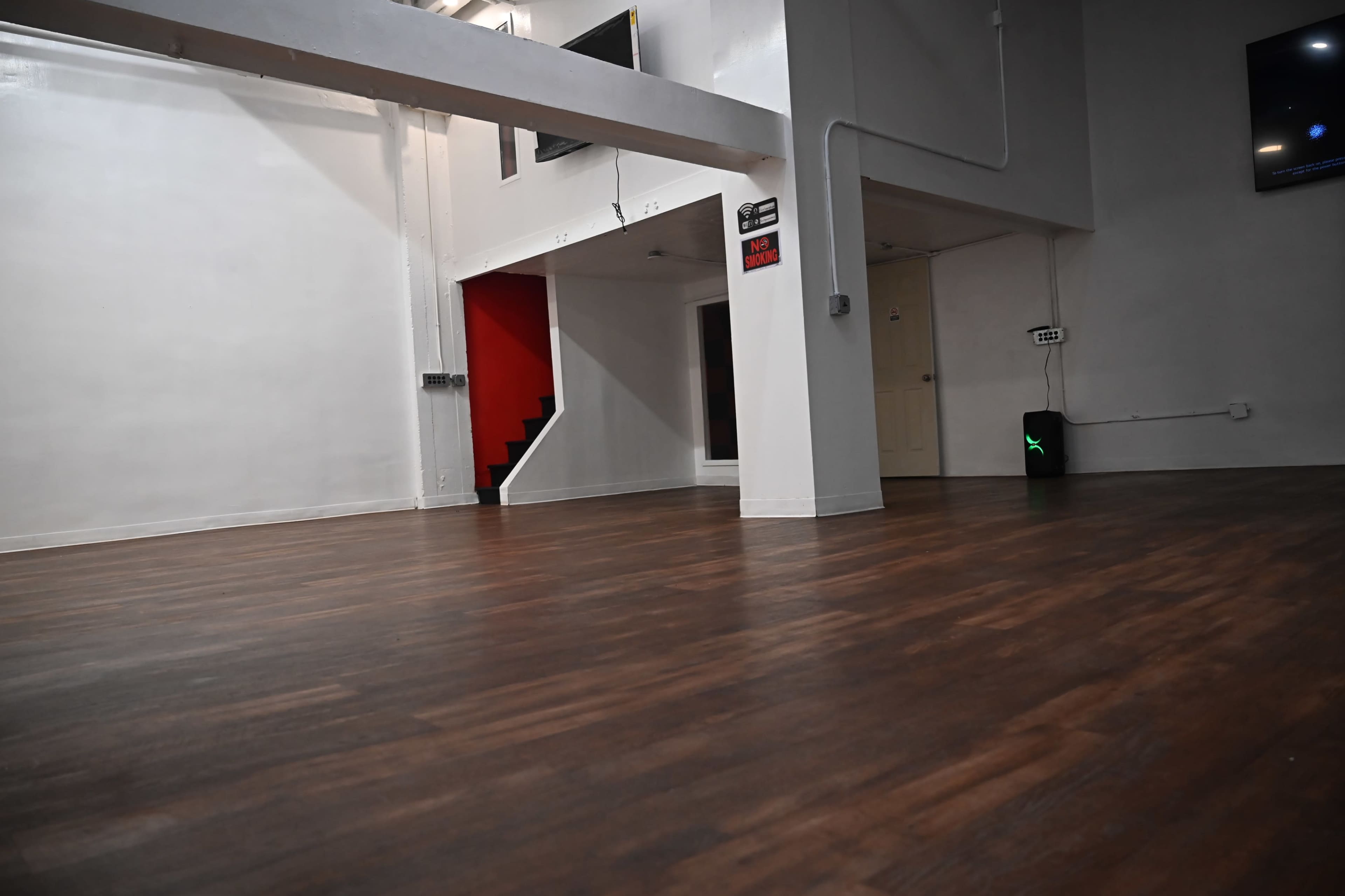 A spacious, empty room with hardwood flooring and a staircase leading to an upper level.