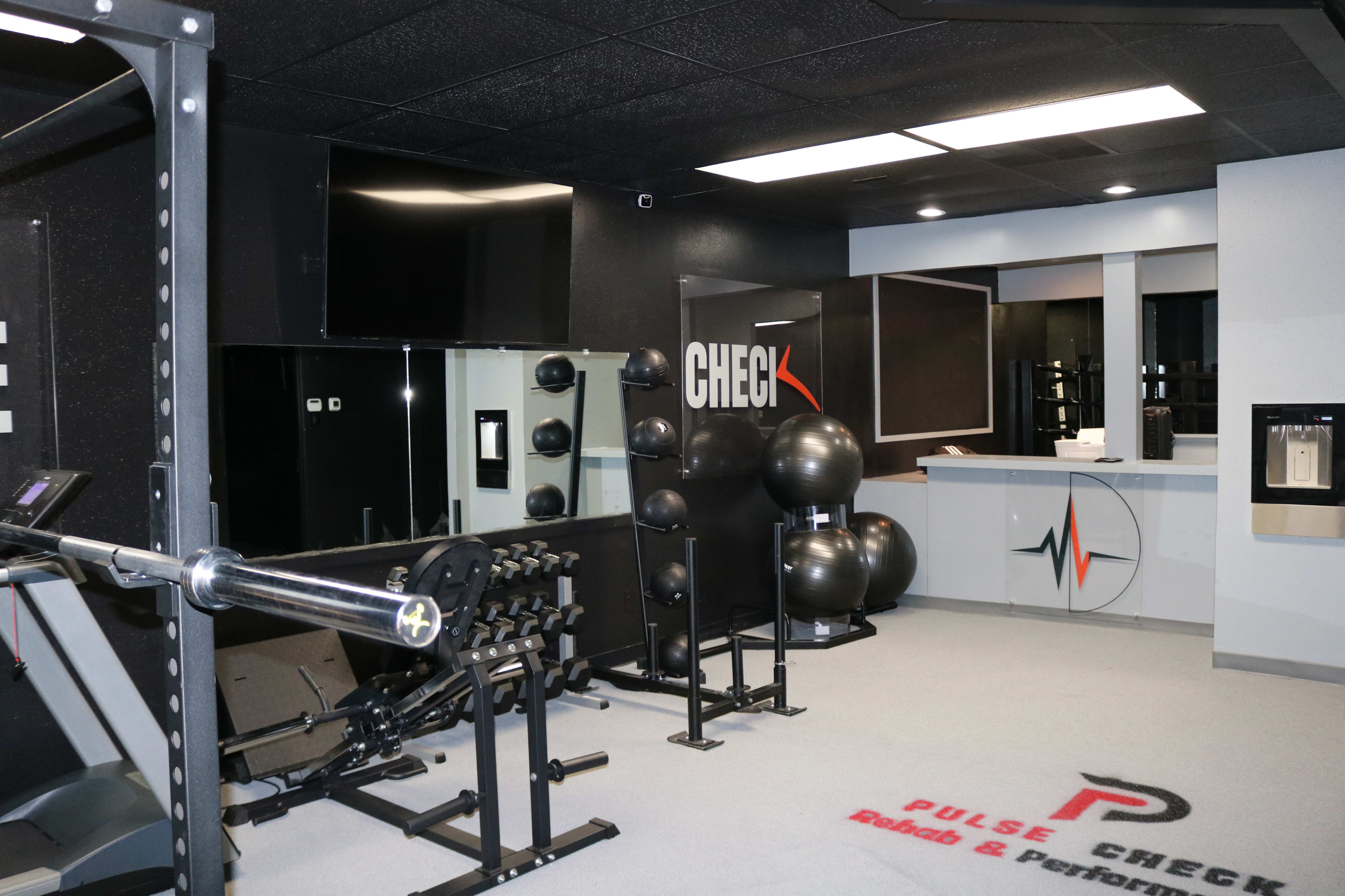 A modern gym interior featuring exercise equipment, free weights, and fitness accessories arranged neatly in a well-lit space.