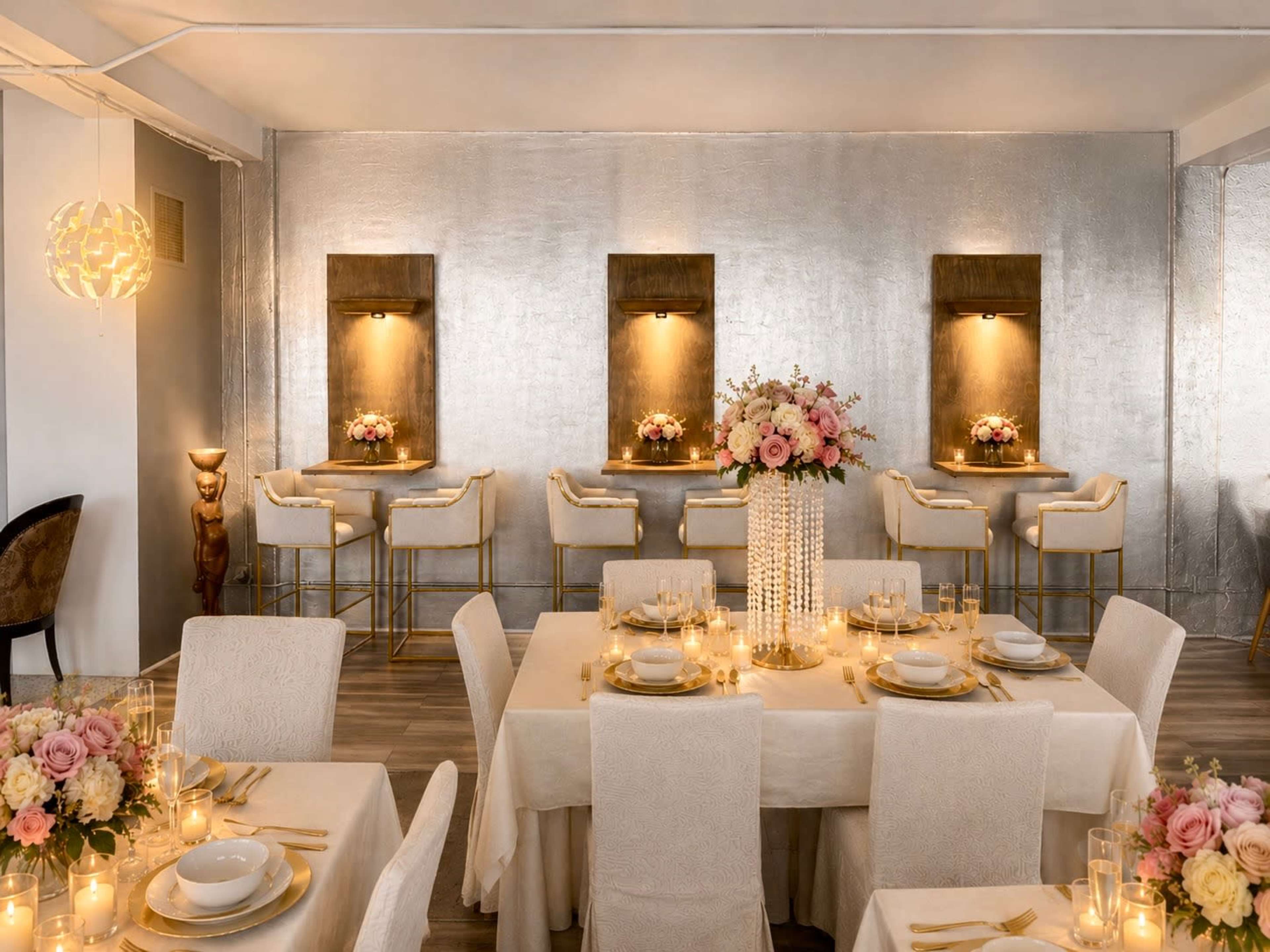 The image shows a light-colored dining area with tables set for a meal, featuring floral centerpieces and illuminated wall displays.