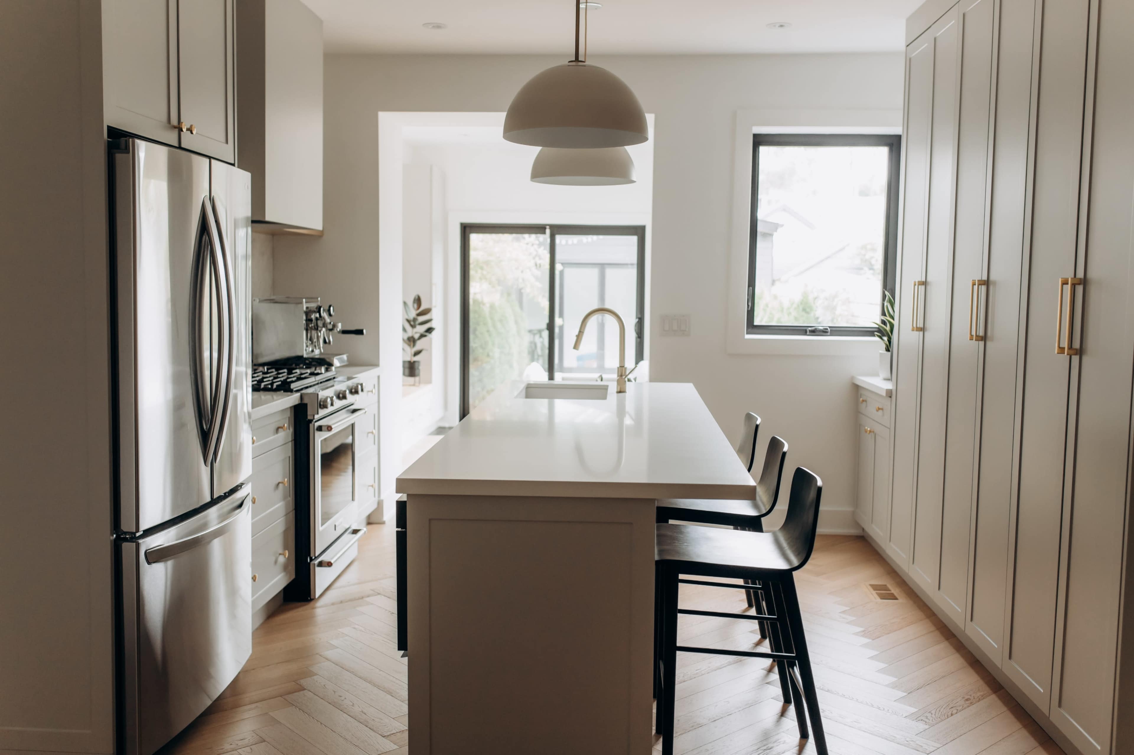 A modern kitchen features stainless steel appliances, a central island with seating, and light-colored cabinetry.