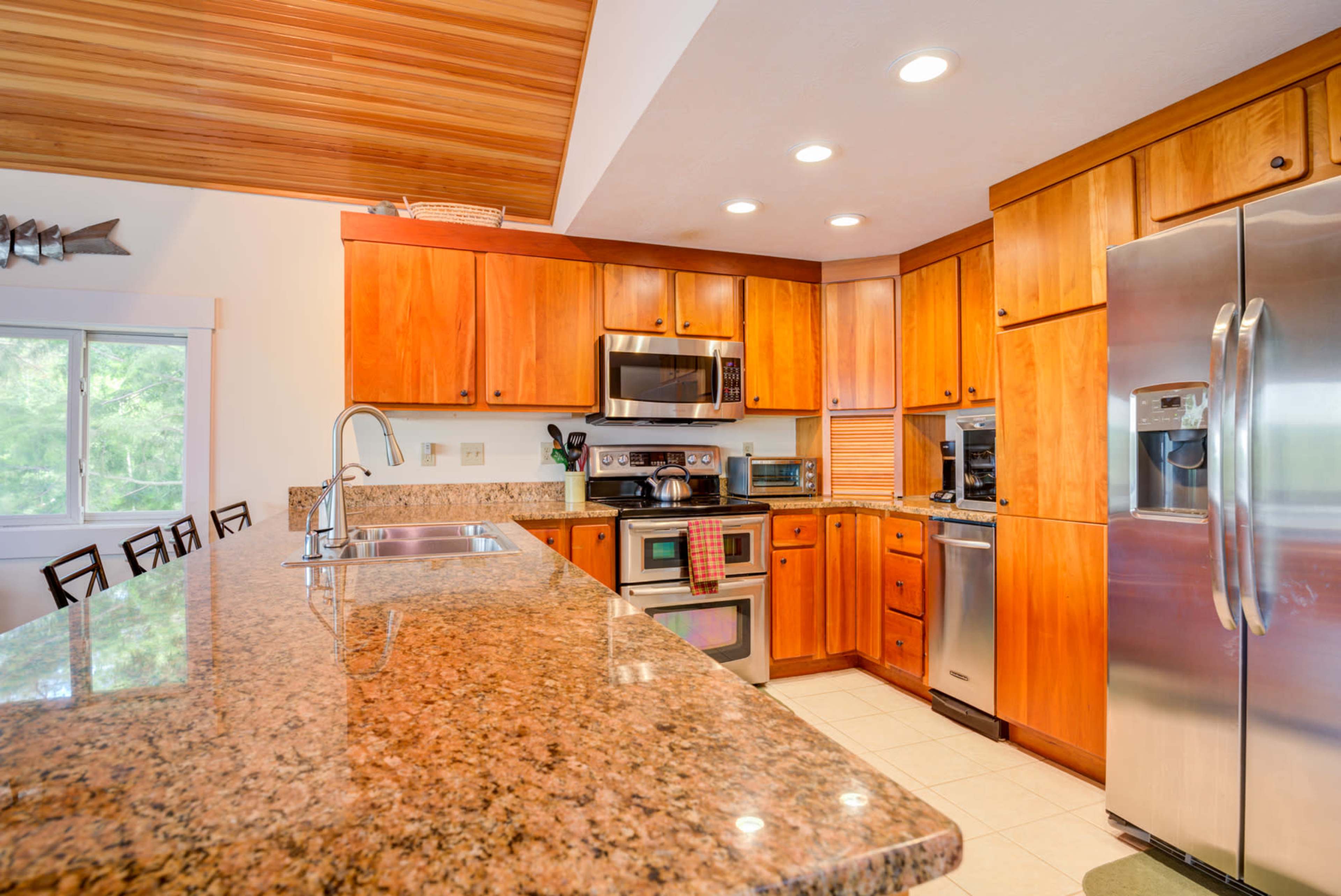 The kitchen features wooden cabinetry, stainless steel appliances, and a granite countertop with a breakfast bar.