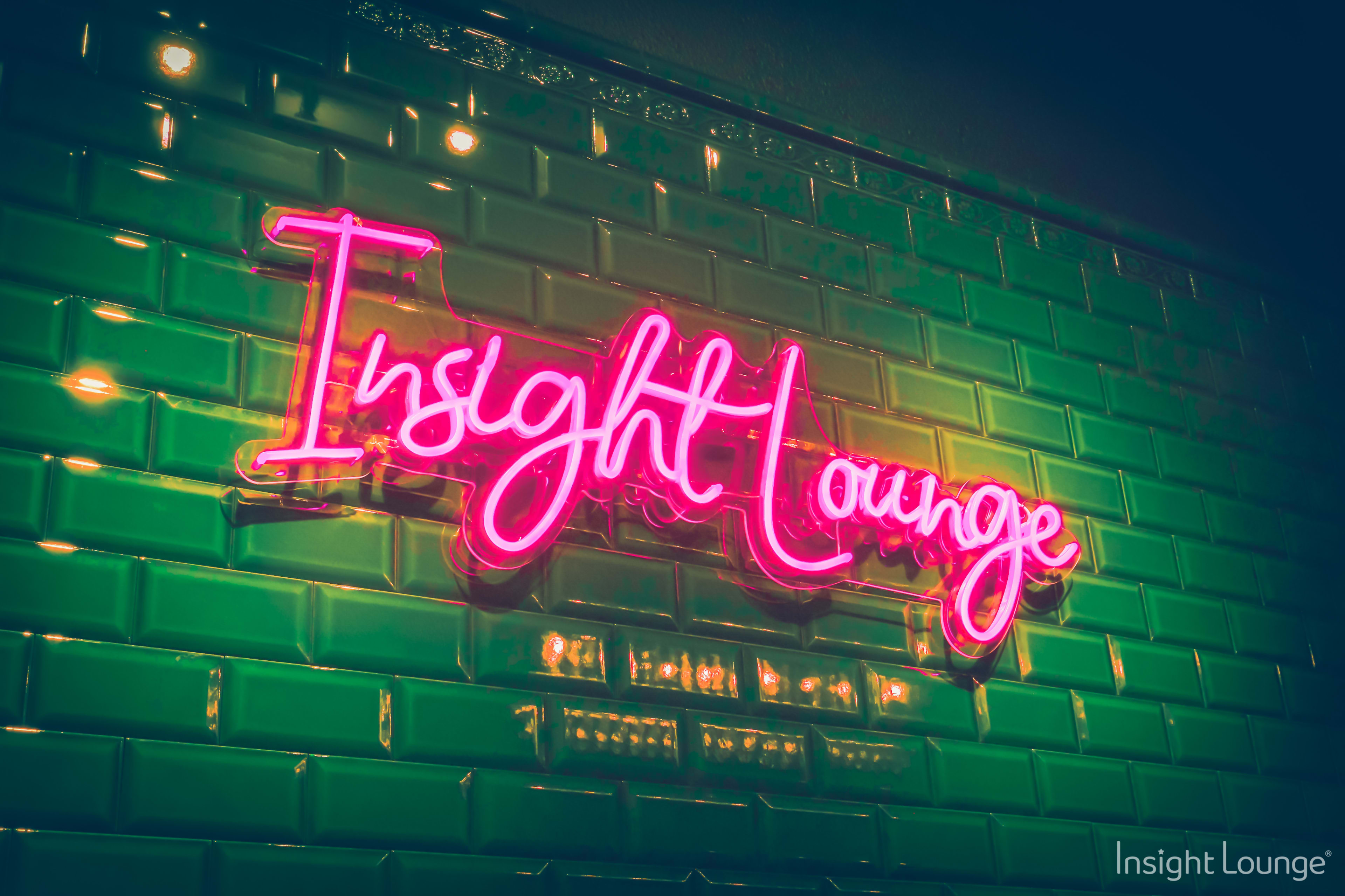 A neon sign that reads "Insight Lounge" against a green tiled wall.