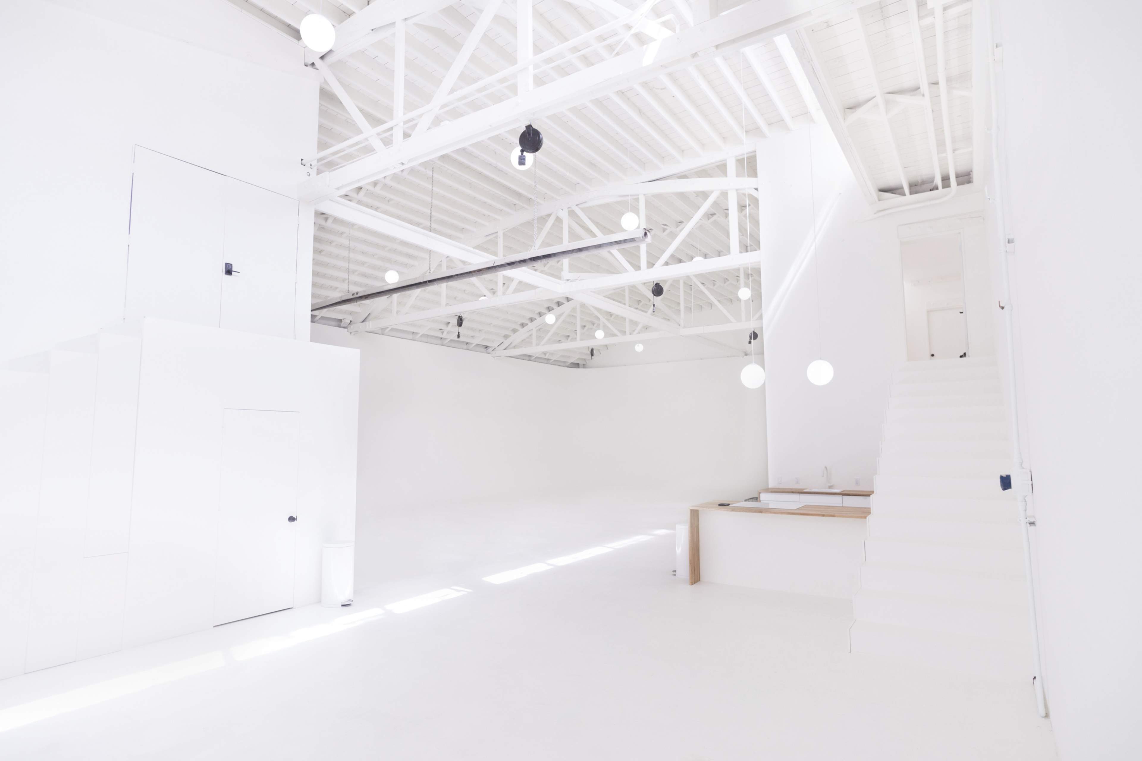 A bright, spacious interior with white walls, a staircase, and minimalist furniture.