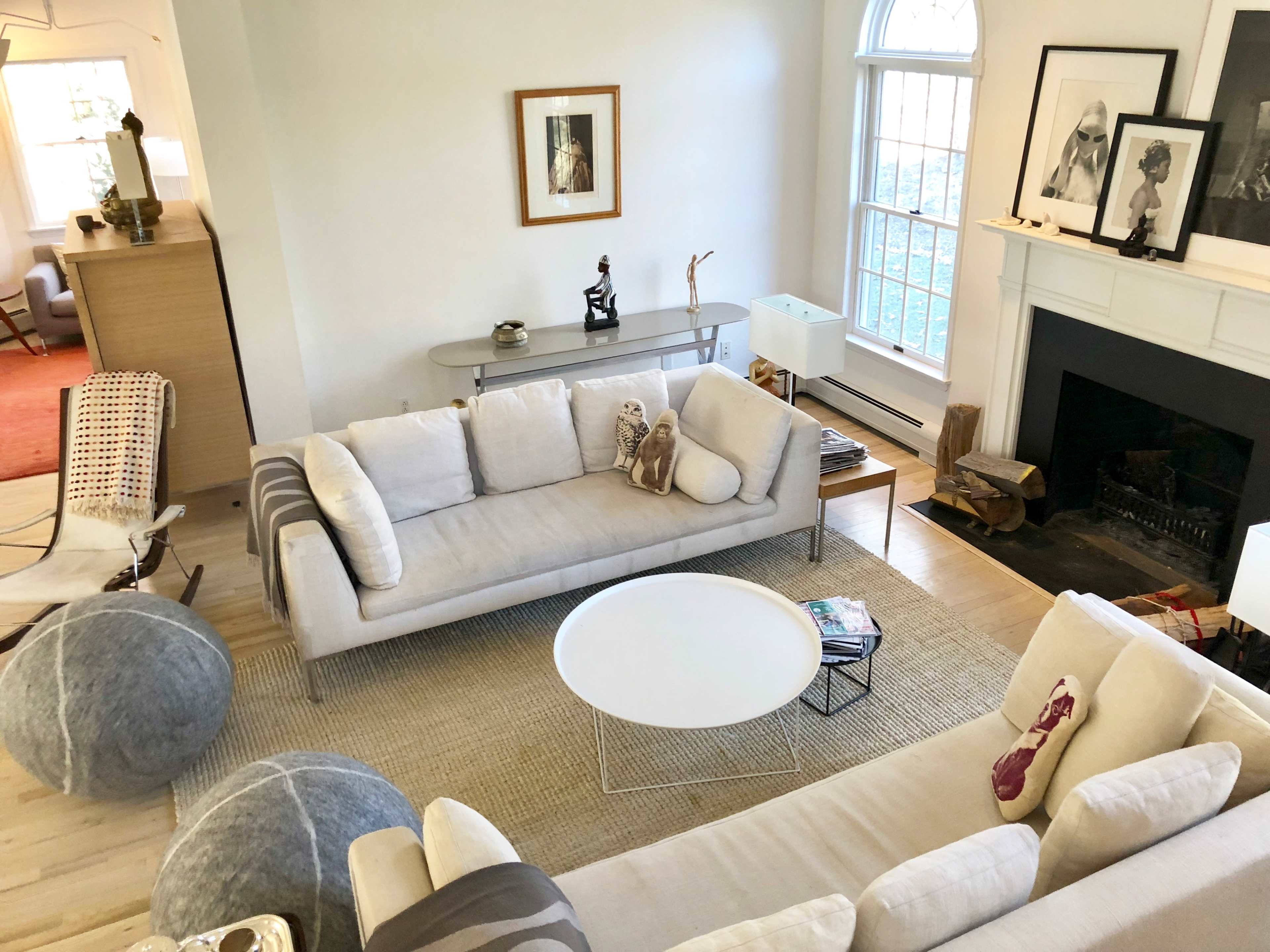 A modern living room with two light-colored sofas, a round coffee table, and artwork displayed on the walls.